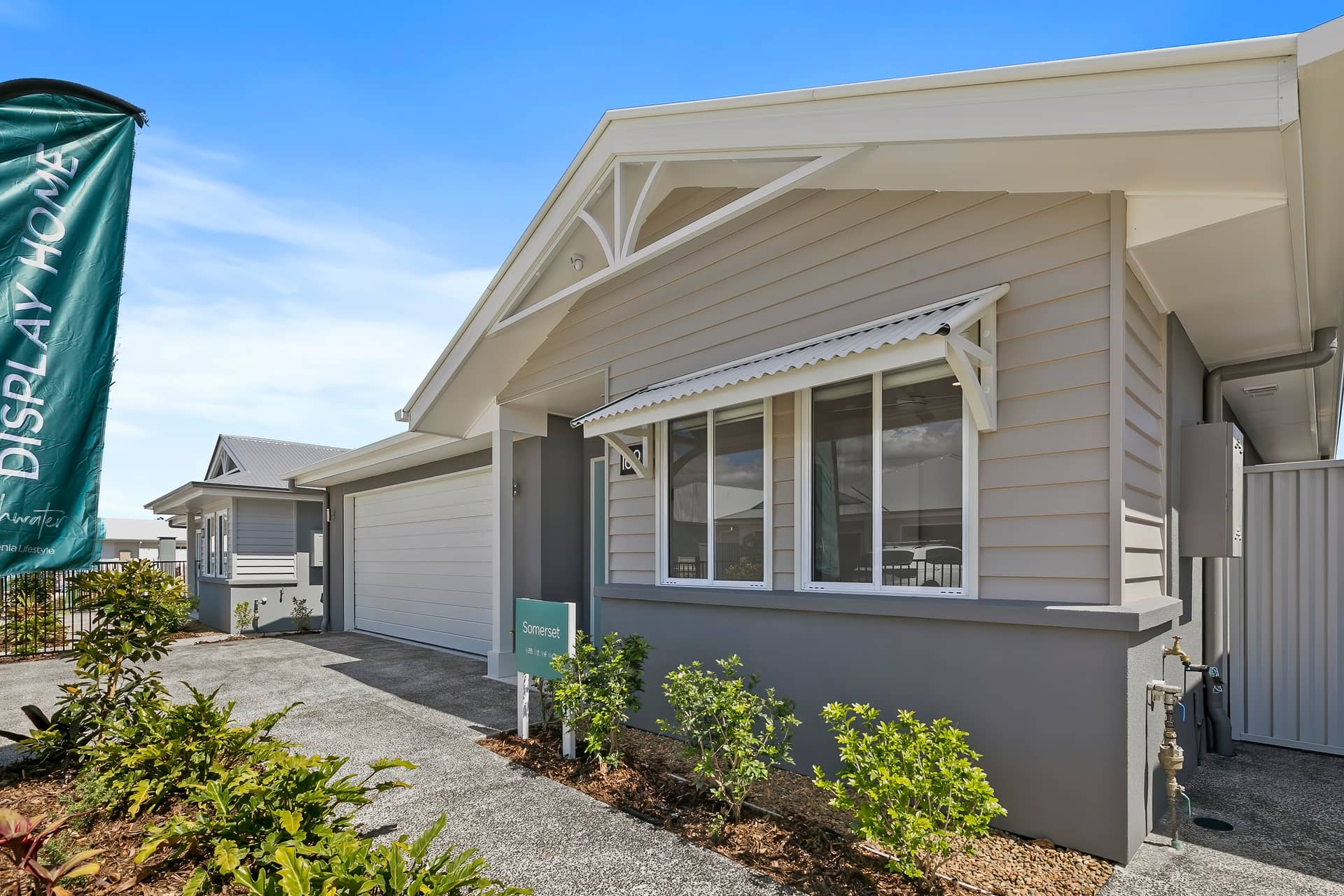 Exterior of an Ingenia Lifestyle land lease display home with light grey facade, white garage, and neat landscaping.