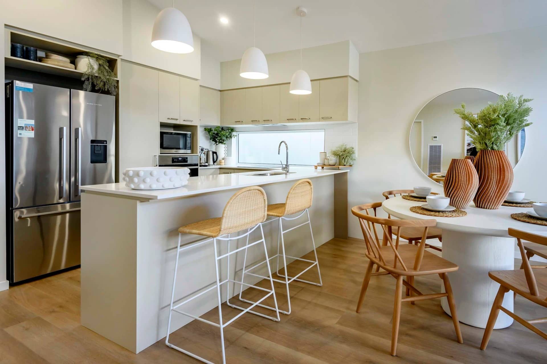 Modern kitchen and dining area in an Ingenia Lifestyle home, featuring a stainless steel fridge, island bench with bar stools, and a round dining table.