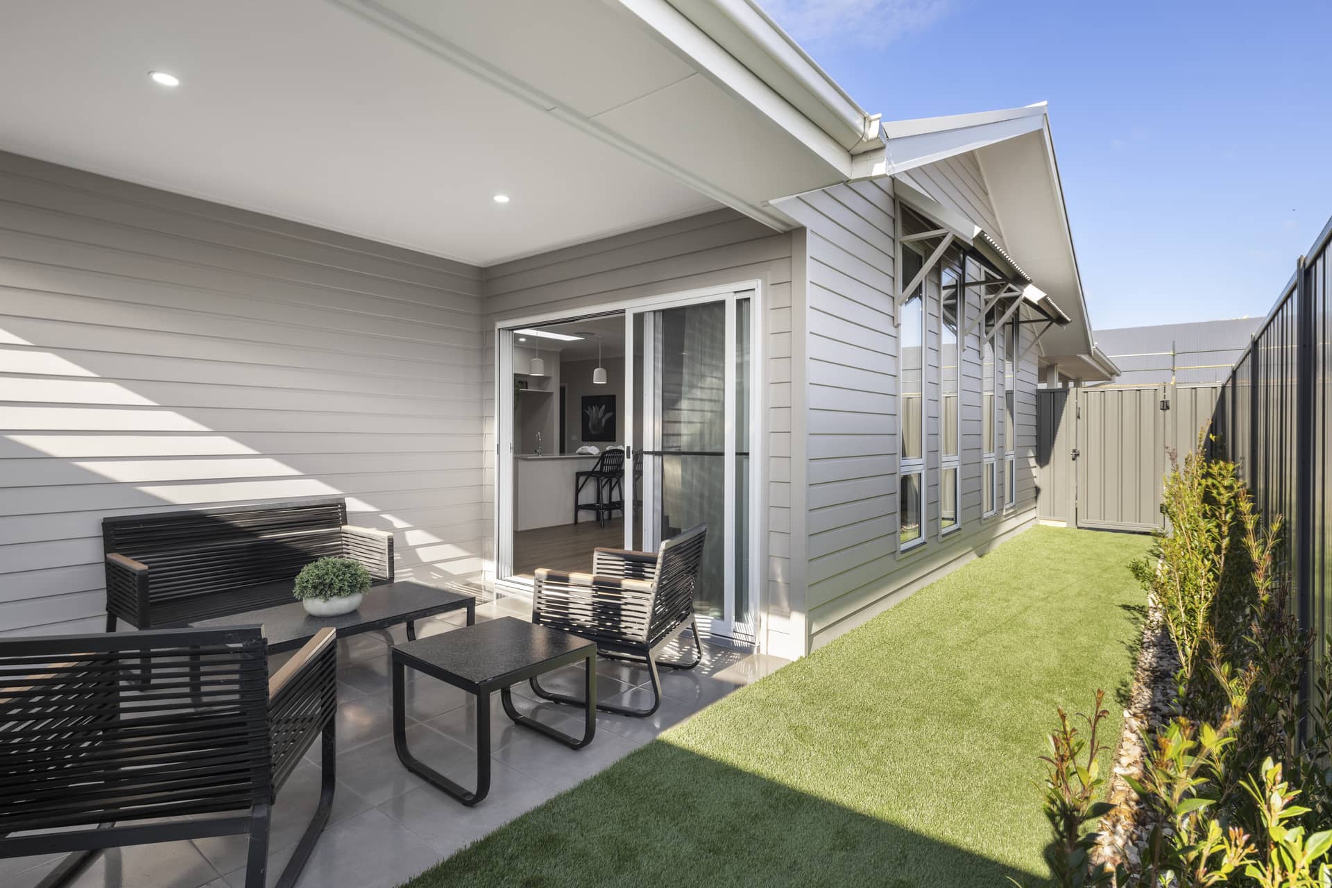 Modern outdoor patio with seating area, sliding doors and low-maintenance landscaping.