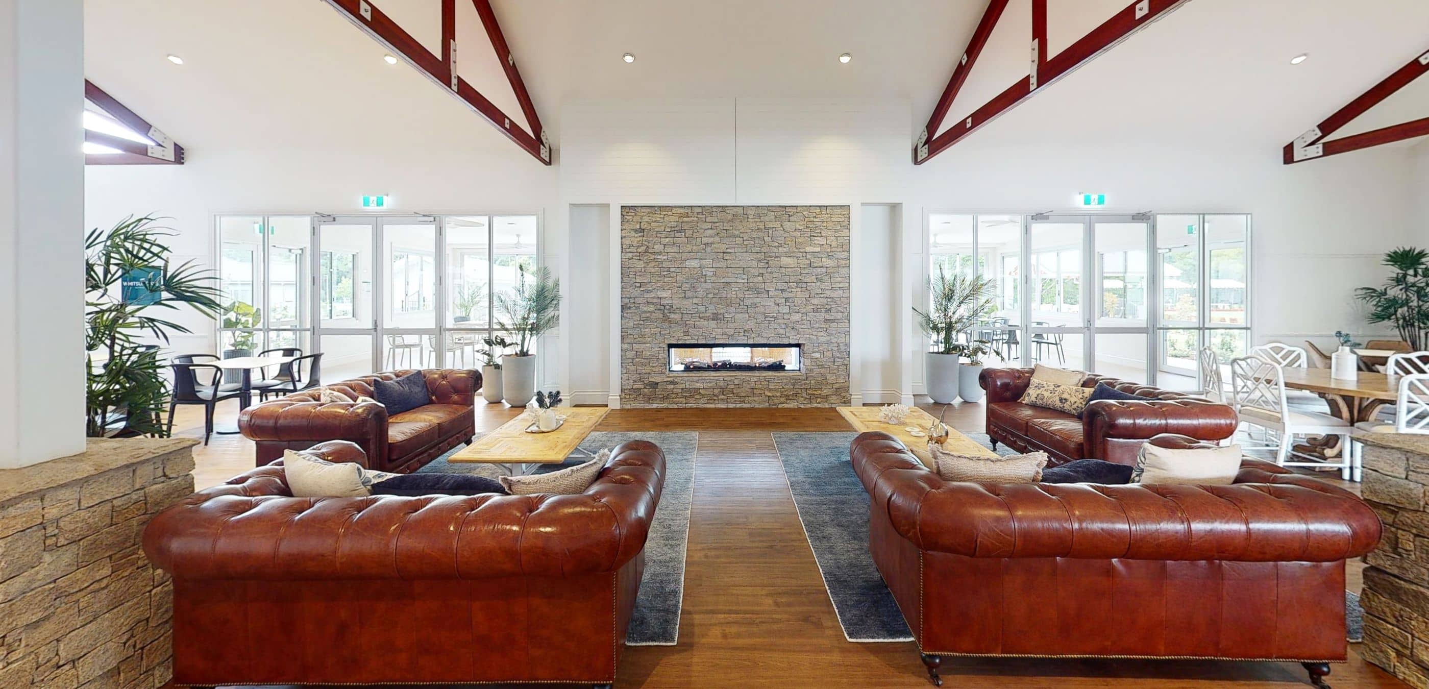 A spacious lounge area in an Ingenia Lifestyle community with leather sofas and a stone fireplace.