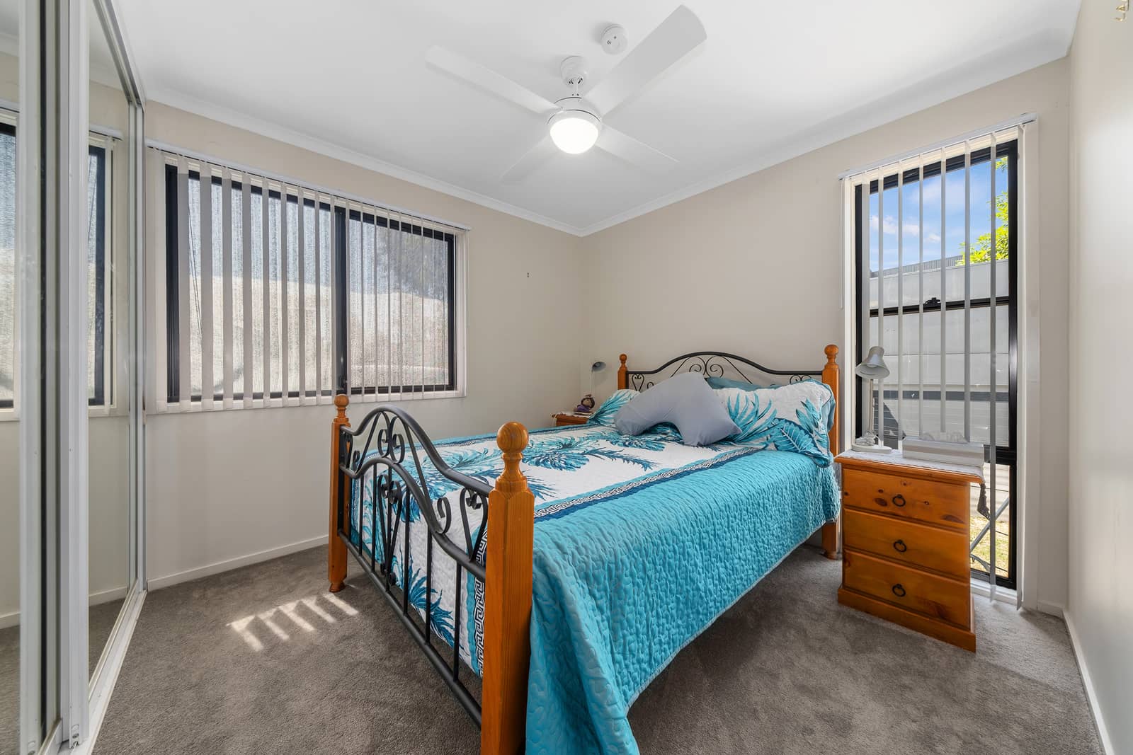 A bedroom in an Ingenia Lifestyle community, featuring a queen-sized bed, bedside table, and ceiling fan.