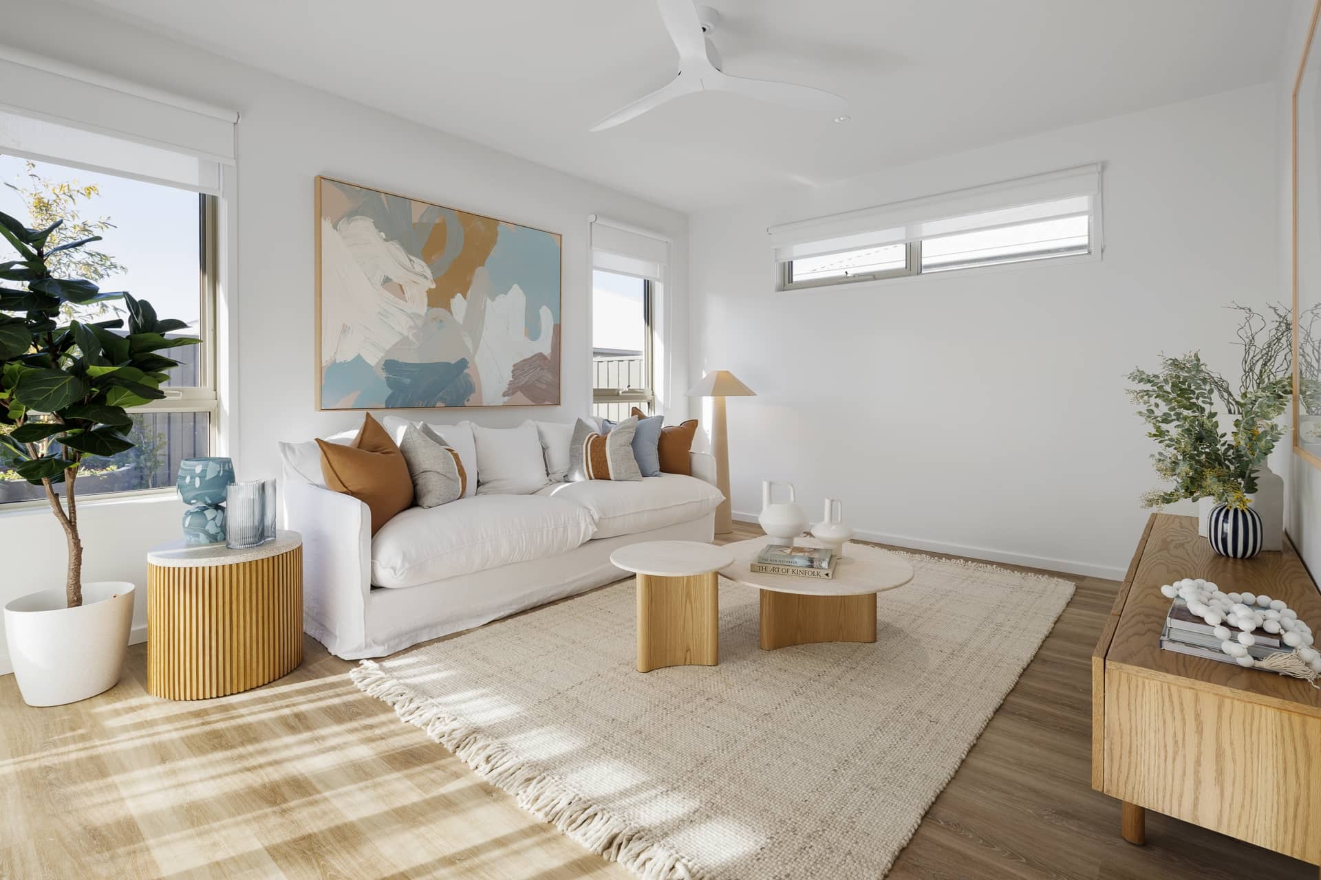 Bright, modern living room in an Ingenia Lifestyle over-55 home, featuring a white sofa, abstract art, and neutral low-maintenance décor.
