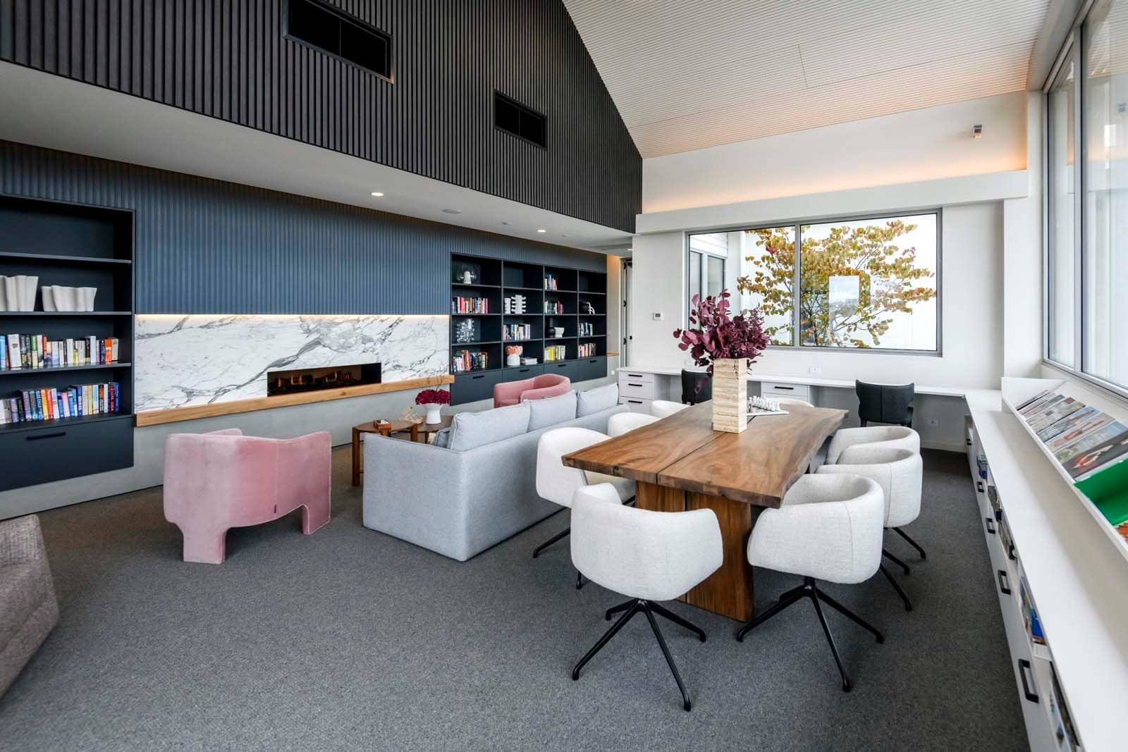 Modern shared facility in an Ingenia Lifestyle community with lounge seating, a fireplace, library, and work desks.