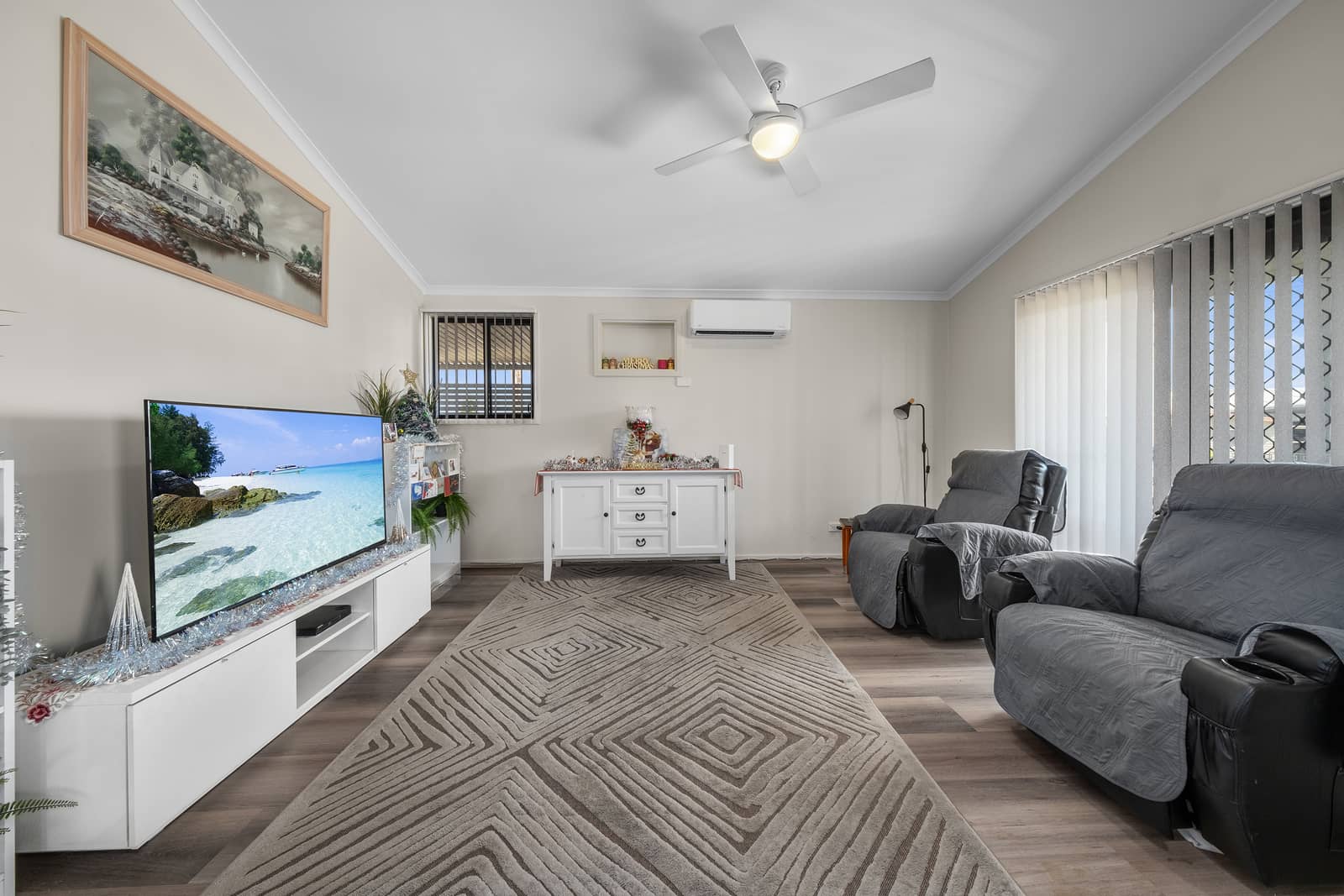 A living room with a TV, two recliners, and a white sideboard in an Ingenia Lifestyle community.