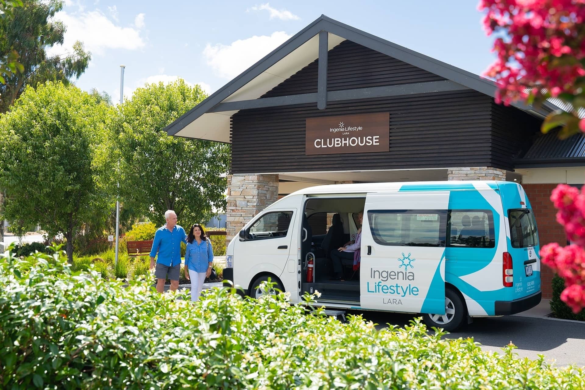 Ingenia Lifestyle community van parked outside the clubhouse with two people walking.