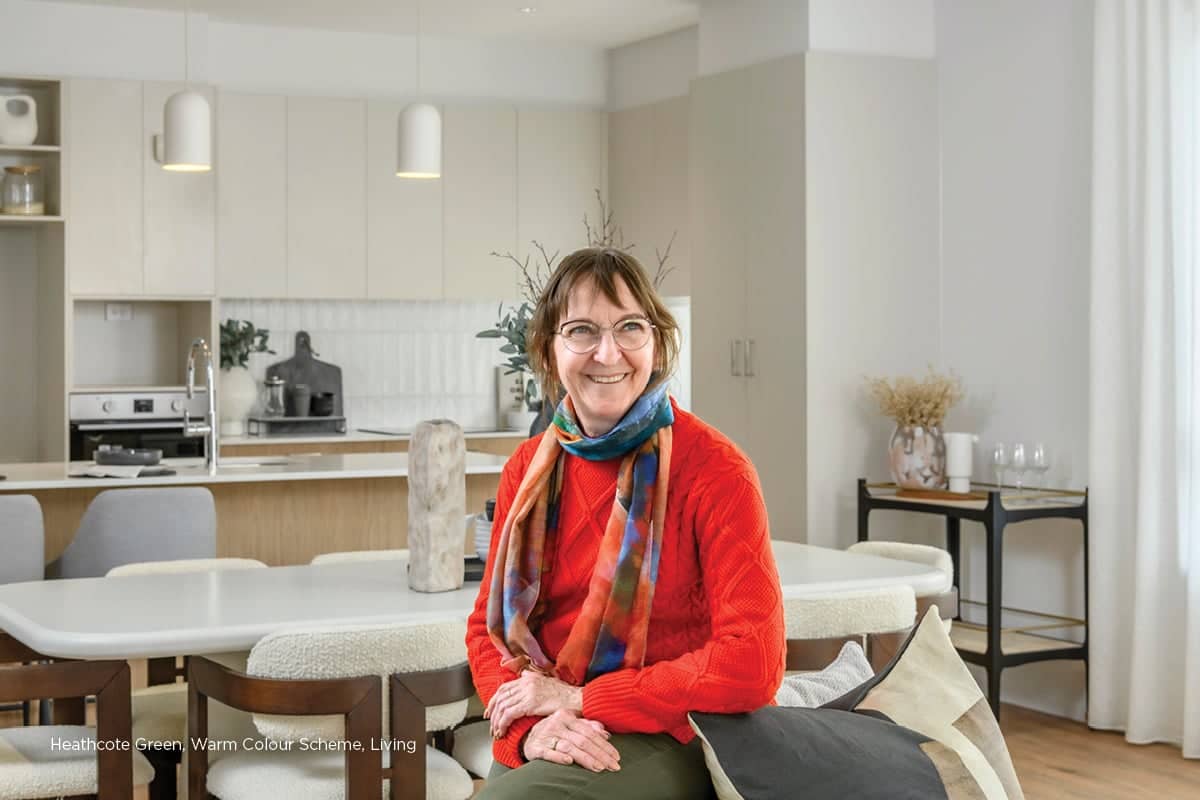 Woman smiling in a bright kitchen and dining area of an Ingenia Lifestyle community home.