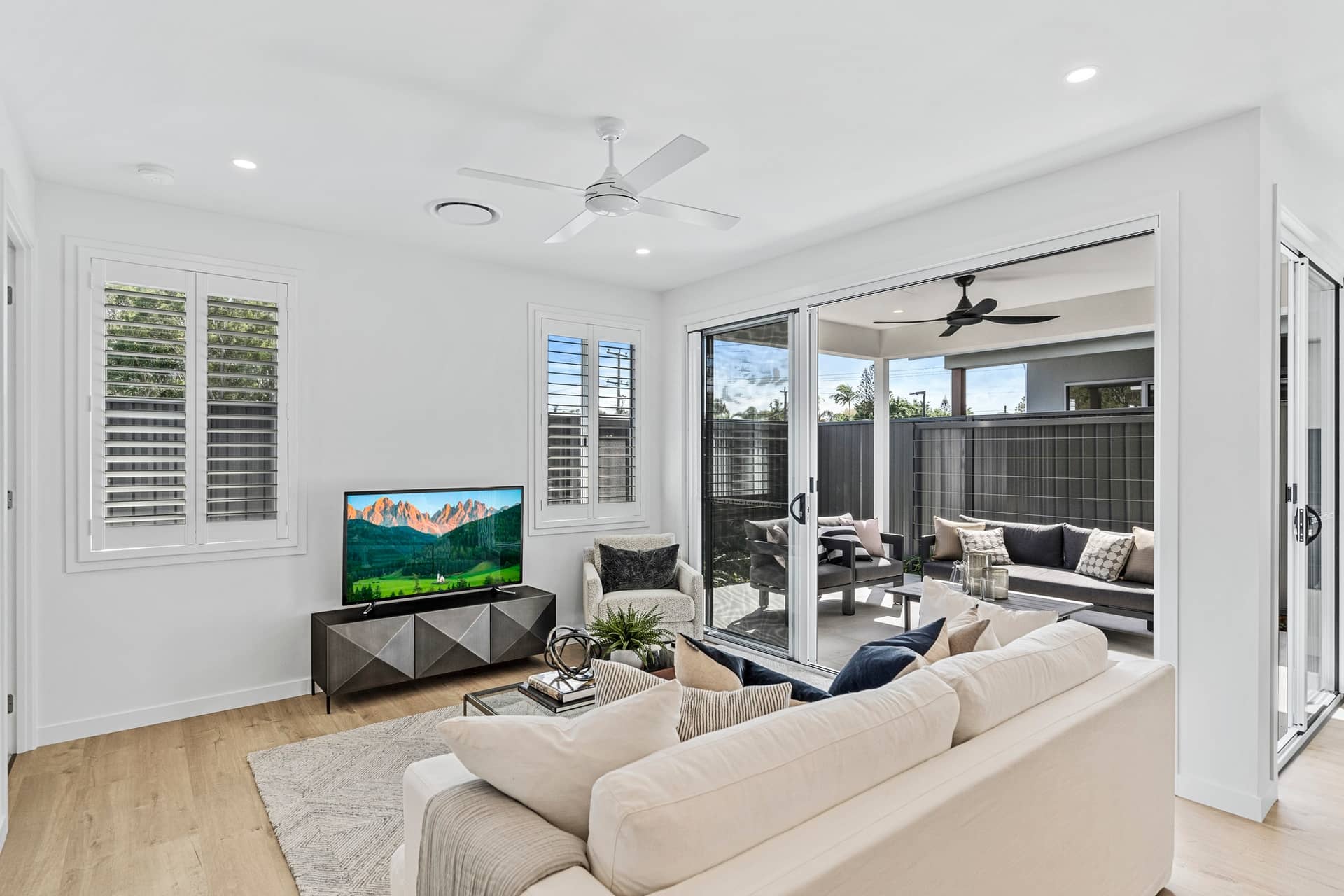 A bright living room with a large TV, comfortable sofa, and sliding doors leading to an outdoor patio.