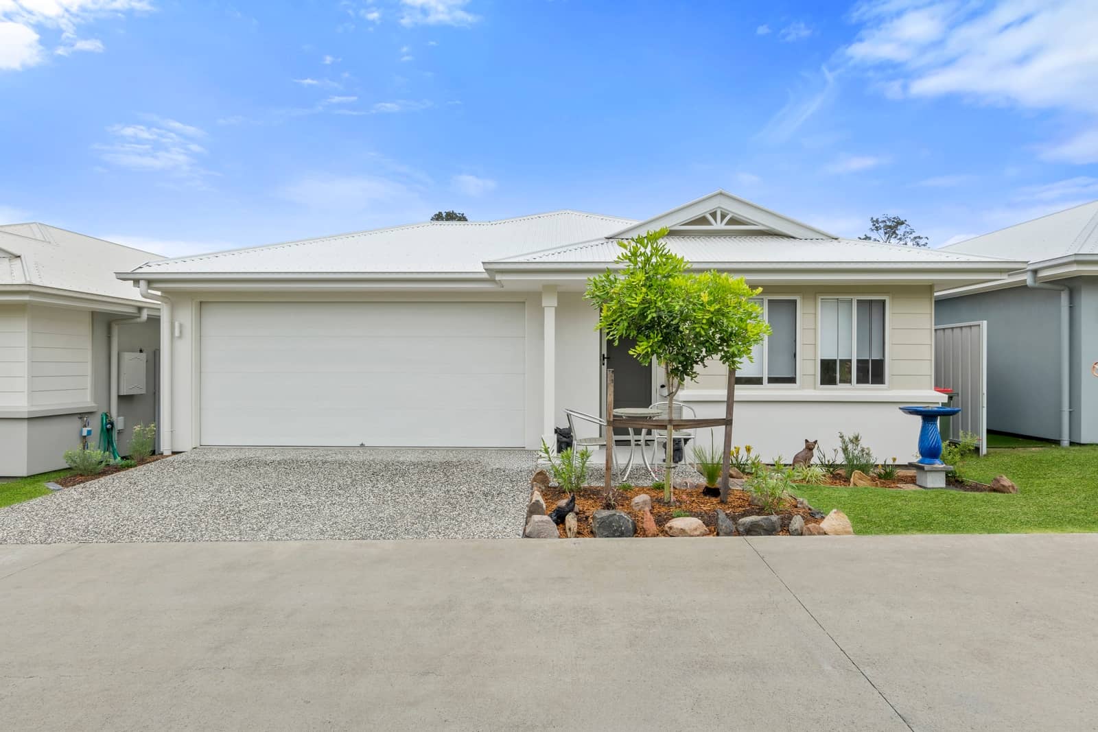 An Ingenia Lifestyle over-55 home with a single garage, landscaped front garden, and small outdoor dining set.