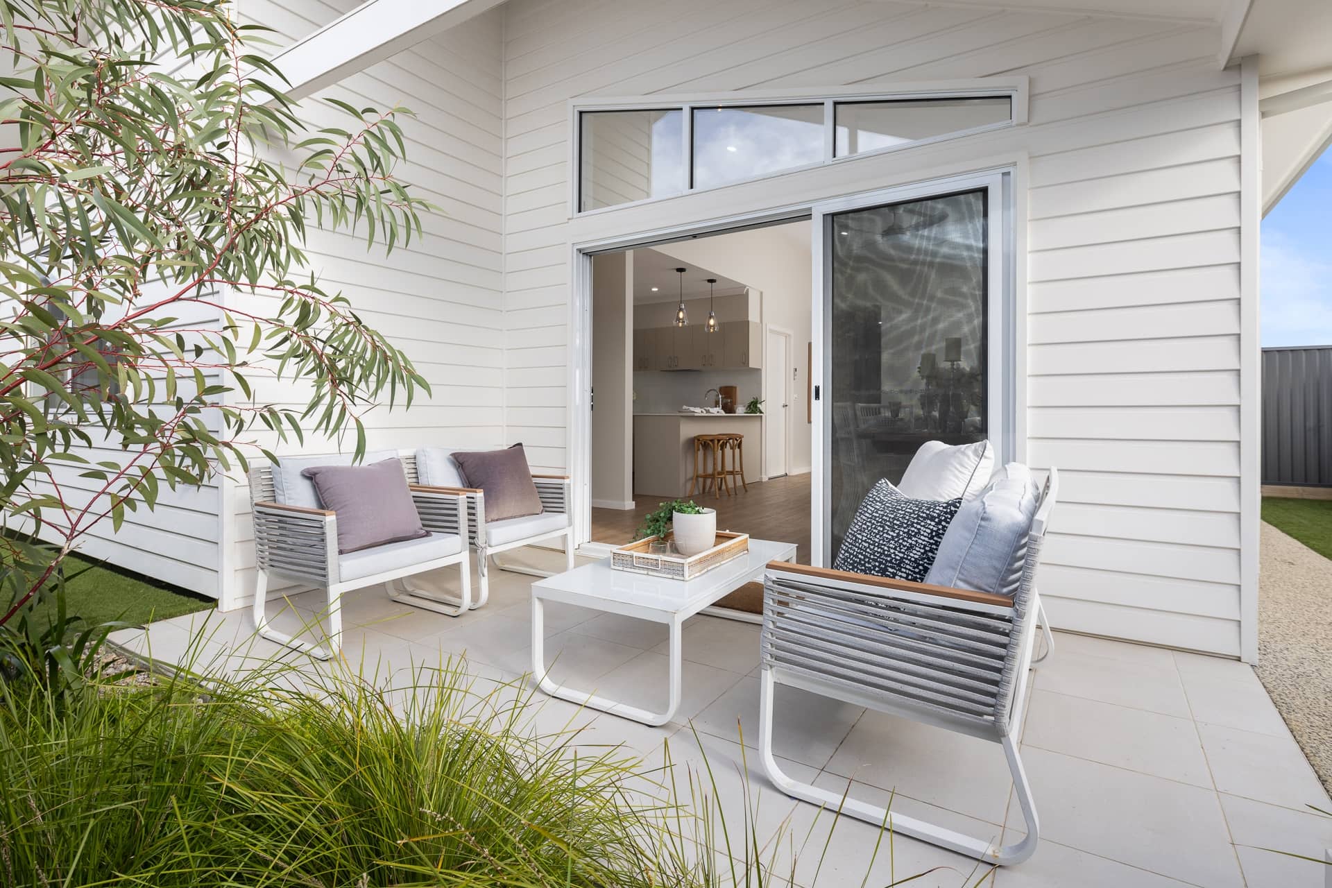 Outdoor patio with seating, coffee table, and view into a modern kitchen.