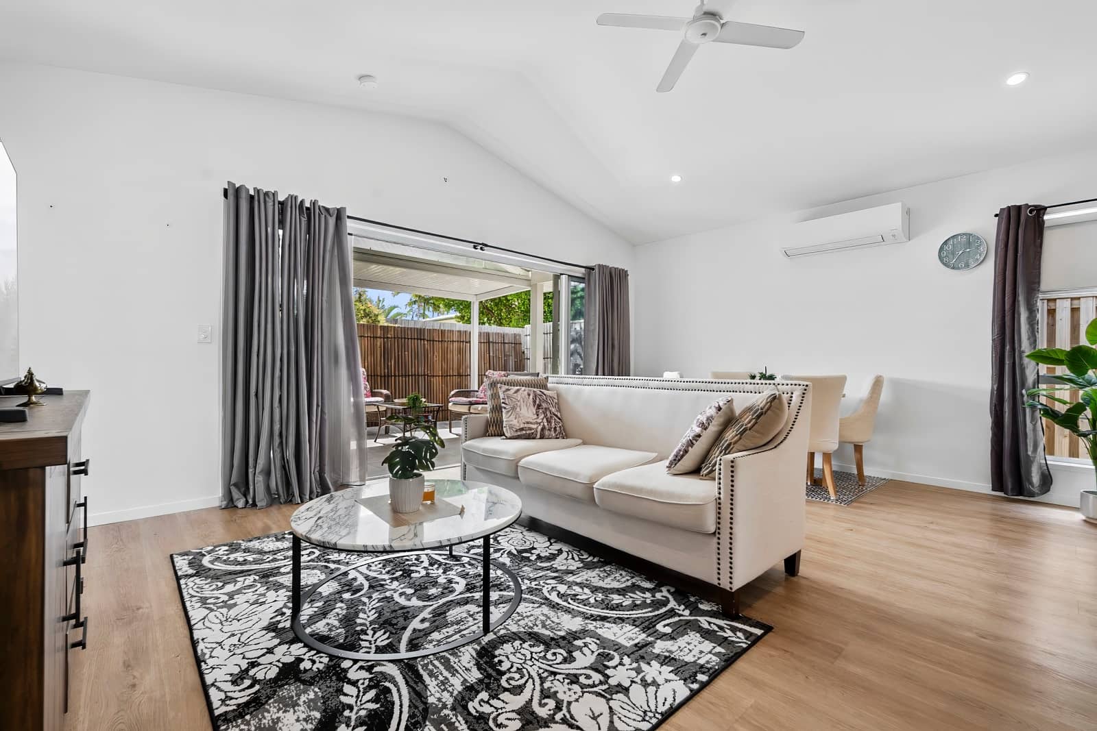 A cream sofa with decorative pillows sits on a patterned rug in a living area.