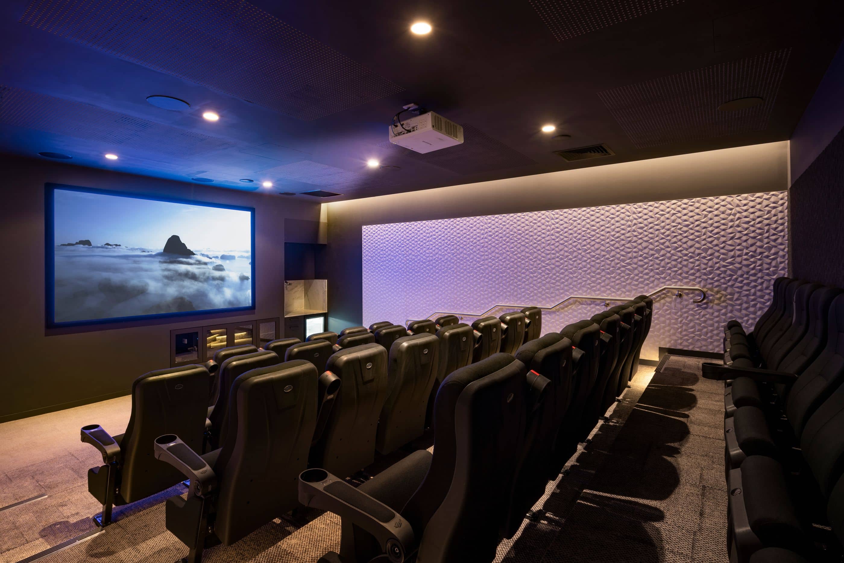 Ingenia Lifestyle community cinema room with black tiered seating, large screen, and a projector.