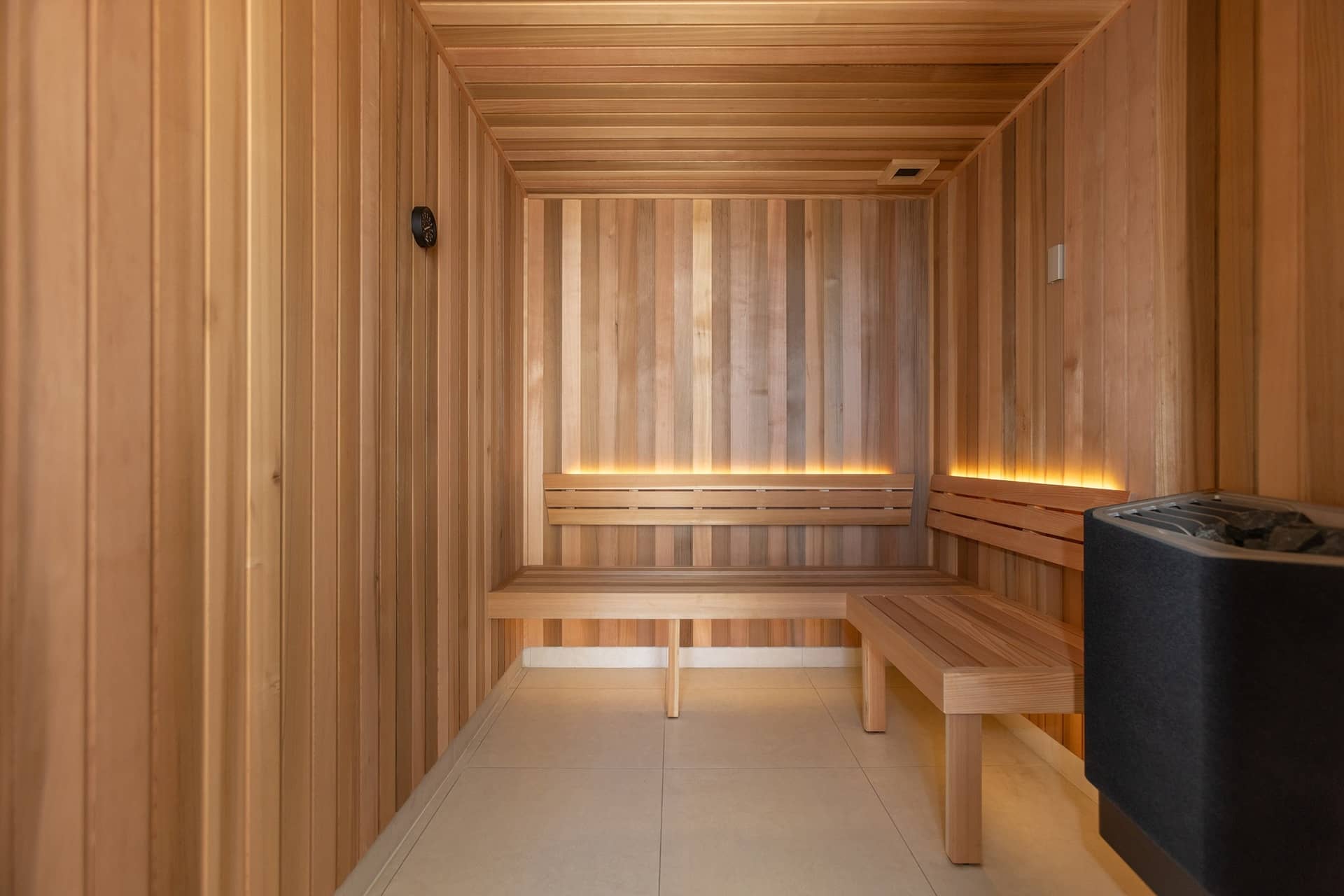 Interior view of a wooden sauna with tiered benches and subtle lighting.