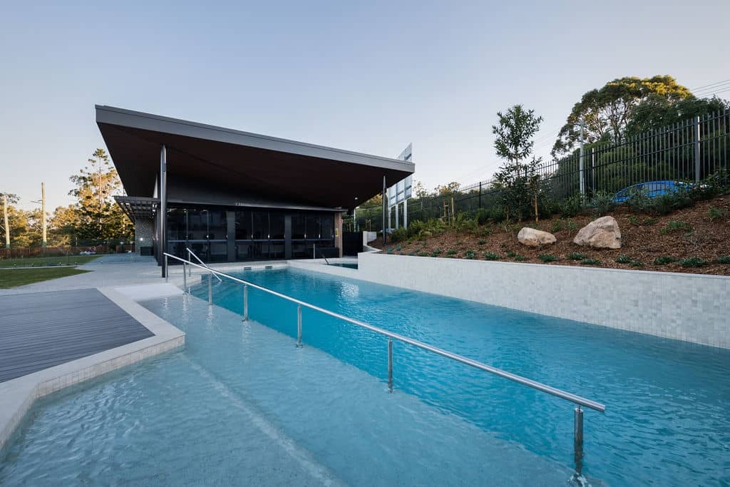 Modern clubhouse and swimming pool with deck and landscaped garden at an Ingenia Lifestyle community.