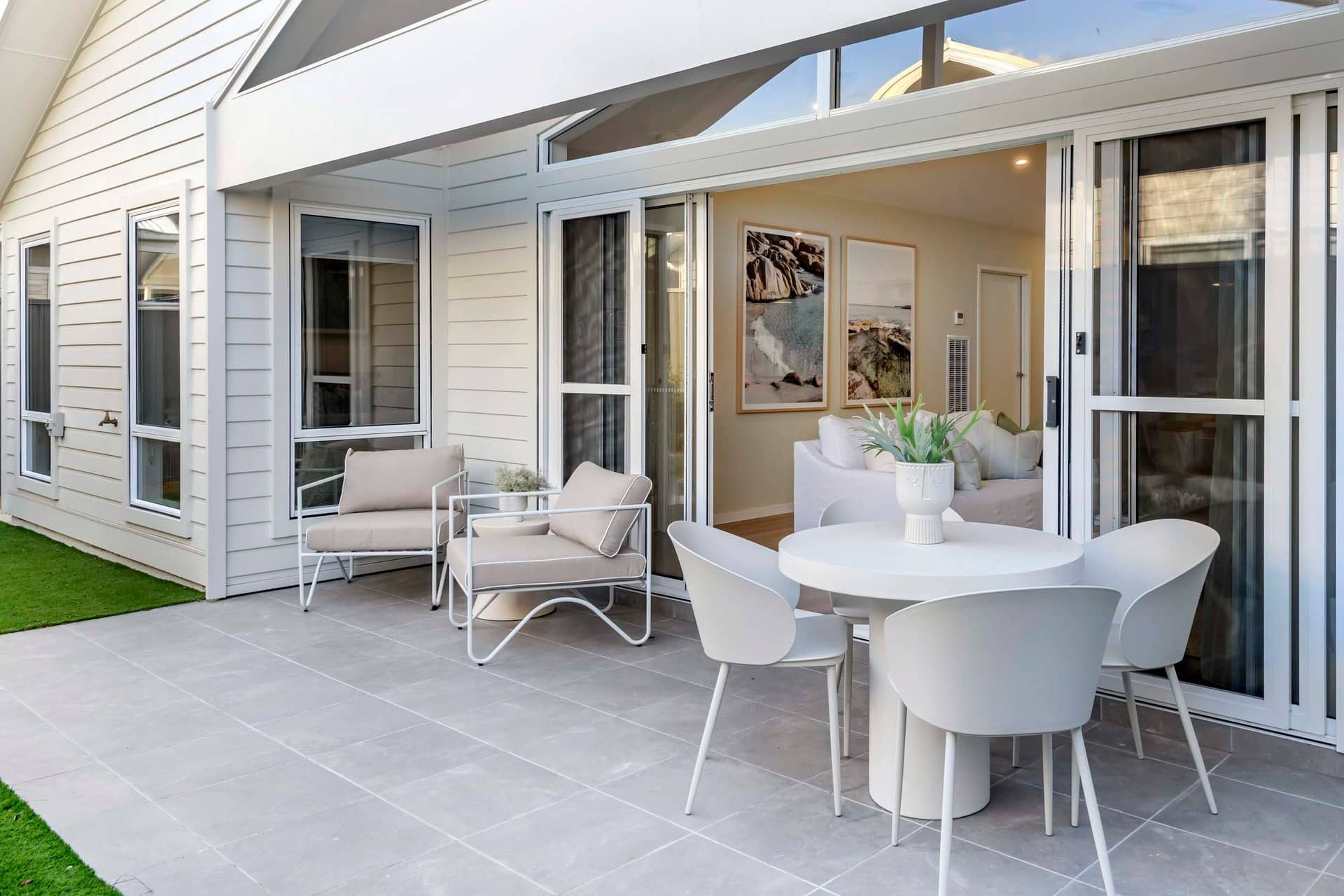 Patio with a white dining set and chairs, overlooking an Ingenia Lifestyle home interior.