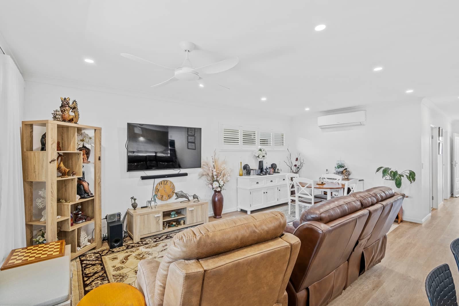 Open plan living and dining area in an Ingenia Lifestyle home, with leather sofas, TV, dining set, ceiling fan, and air conditioning.