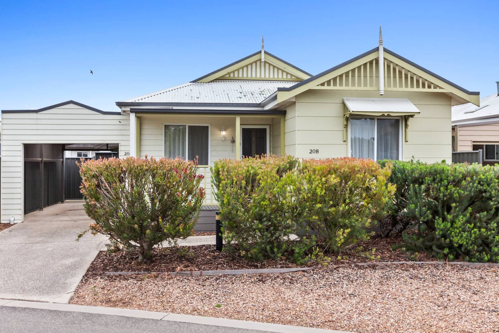 A cream-coloured, single-story land lease home at an Ingenia Lifestyle community, featuring a carport and low-maintenance landscaping.