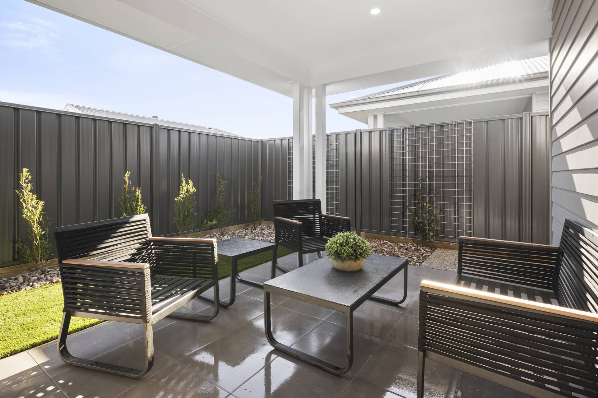 Outdoor patio area with modern seating and tables, enclosed by a fence.