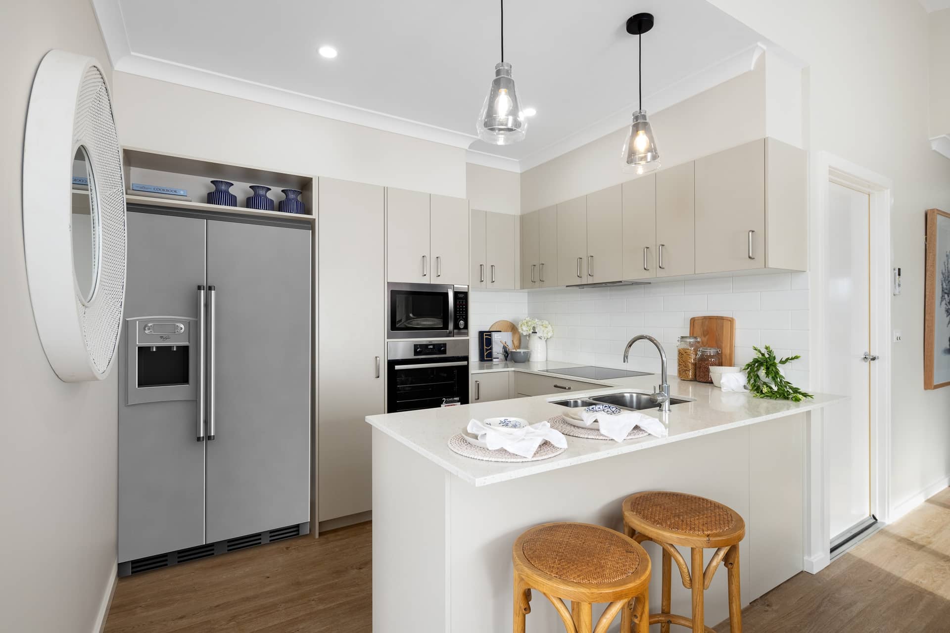 Modern kitchen with a large stainless steel refrigerator, island with seating and kitchen amenities.