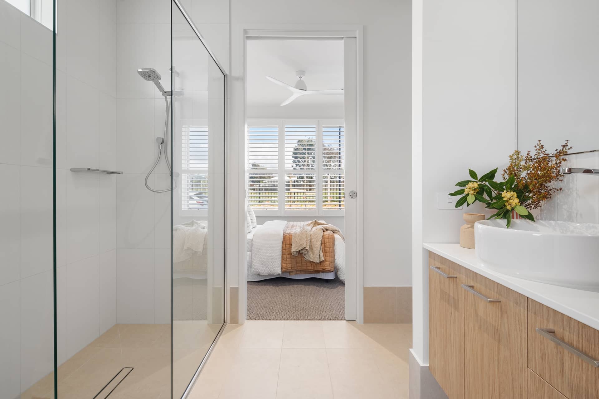 Modern bathroom with a glass shower and vanity, leading to an over-55 Ingenia Lifestyle home bedroom.