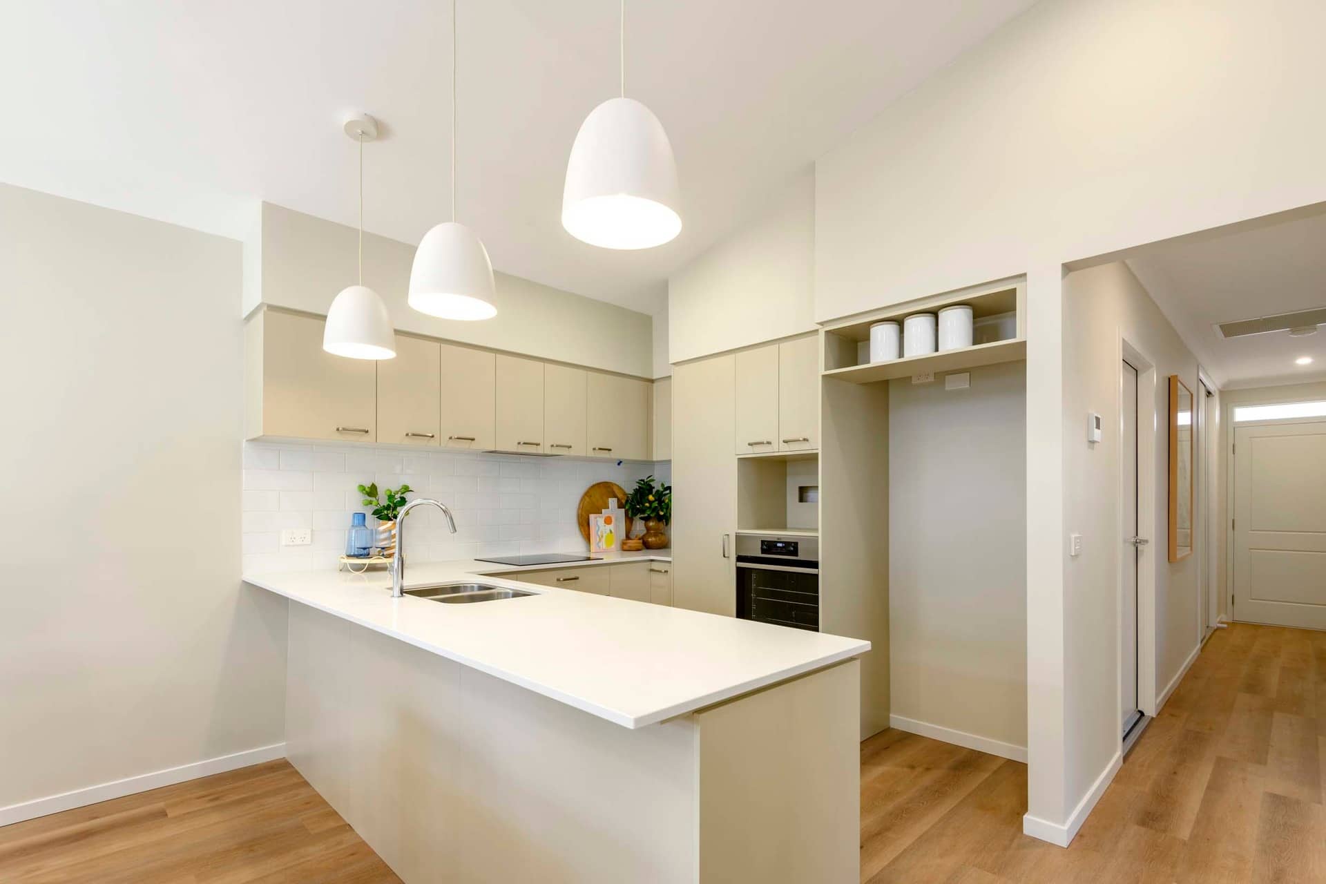 Modern kitchen with island, white countertops, cream cabinetry, and pendant lights in an Ingenia Lifestyle community.