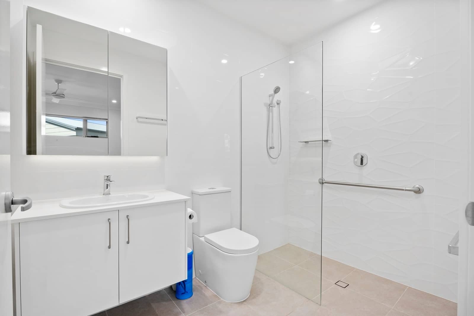 Clean bathroom in an Ingenia Lifestyle home featuring a vanity, toilet, and accessible walk-in shower with grab rail.