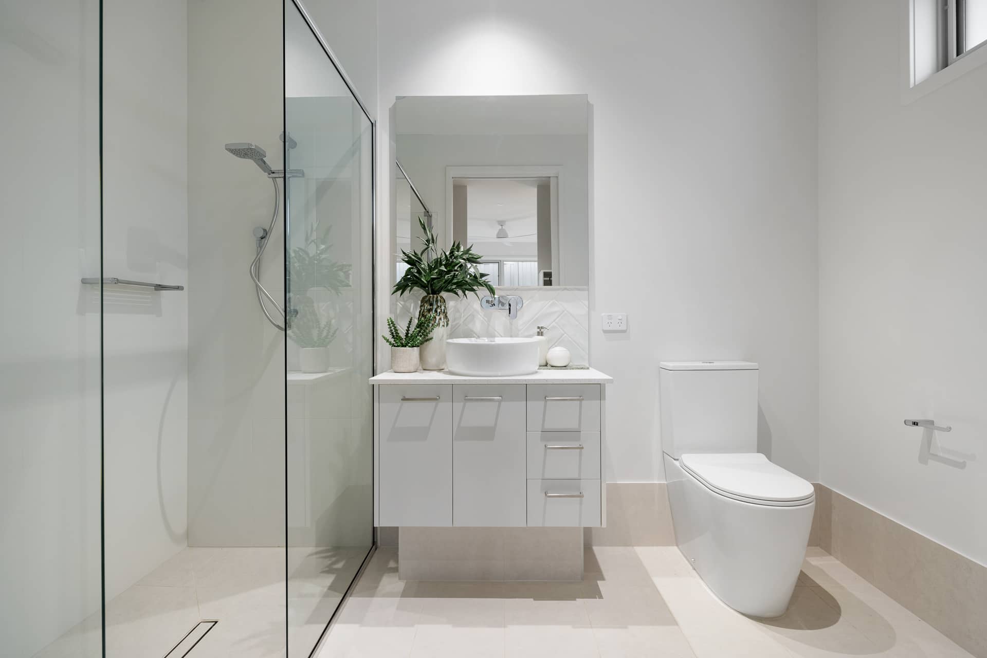 Modern bathroom in an Ingenia Lifestyle home with a glass shower, white floating vanity, basin, and toilet.