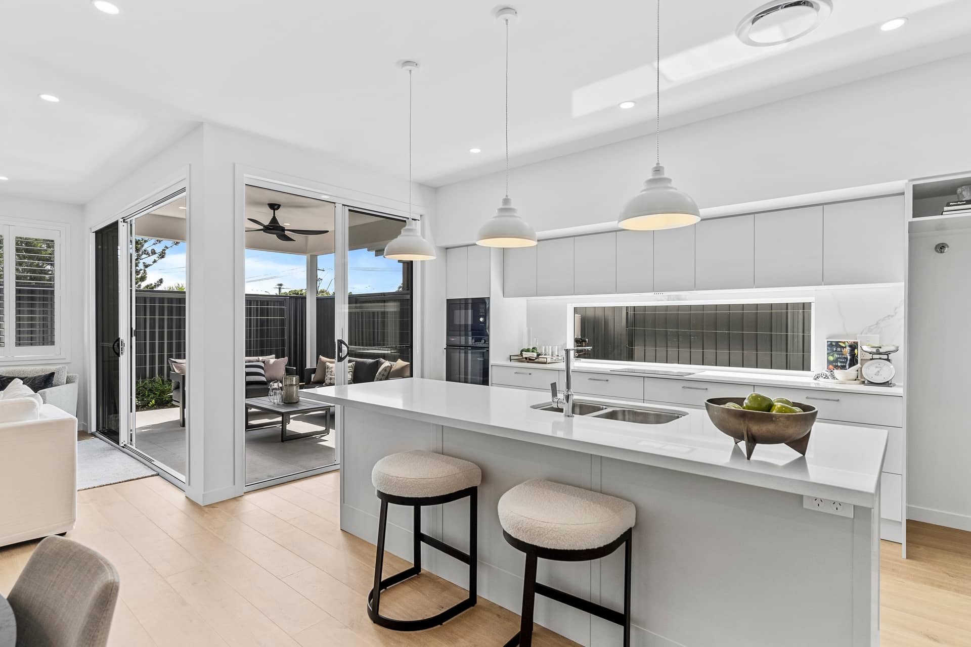 Modern kitchen with island, stools, and view of outdoor entertaining area.