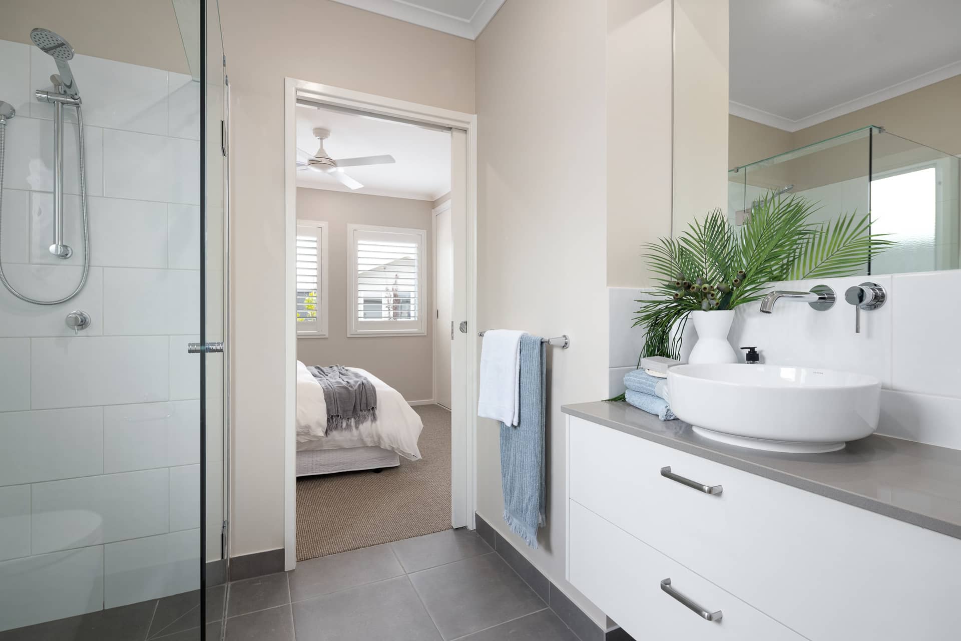 Modern bathroom with walk-in shower, vanity with vessel sink, and view into a bedroom in an Ingenia Lifestyle community.
