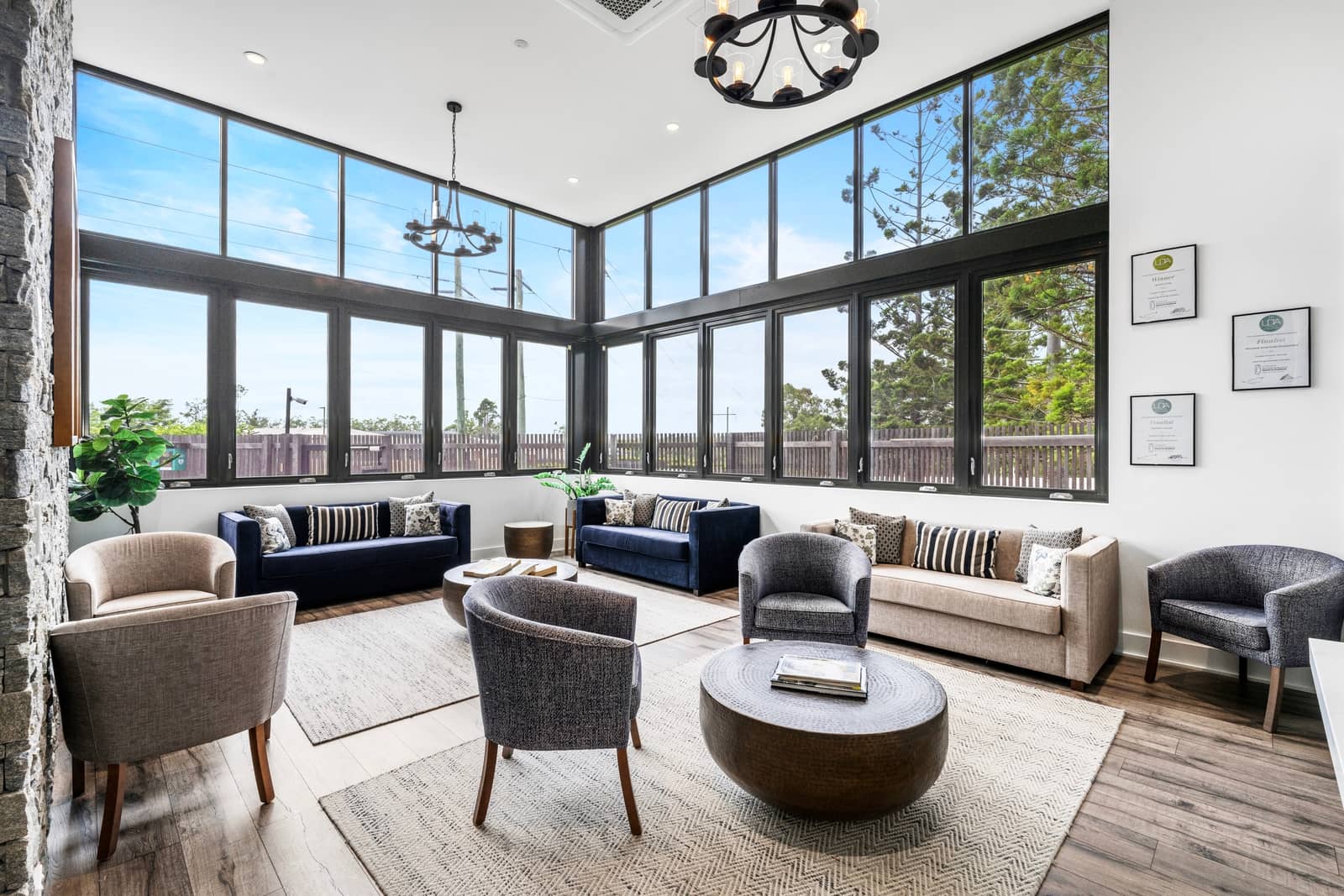 Modern shared lounge with sofas, armchairs, coffee tables, and large windows. An Ingenia Lifestyle community amenity.