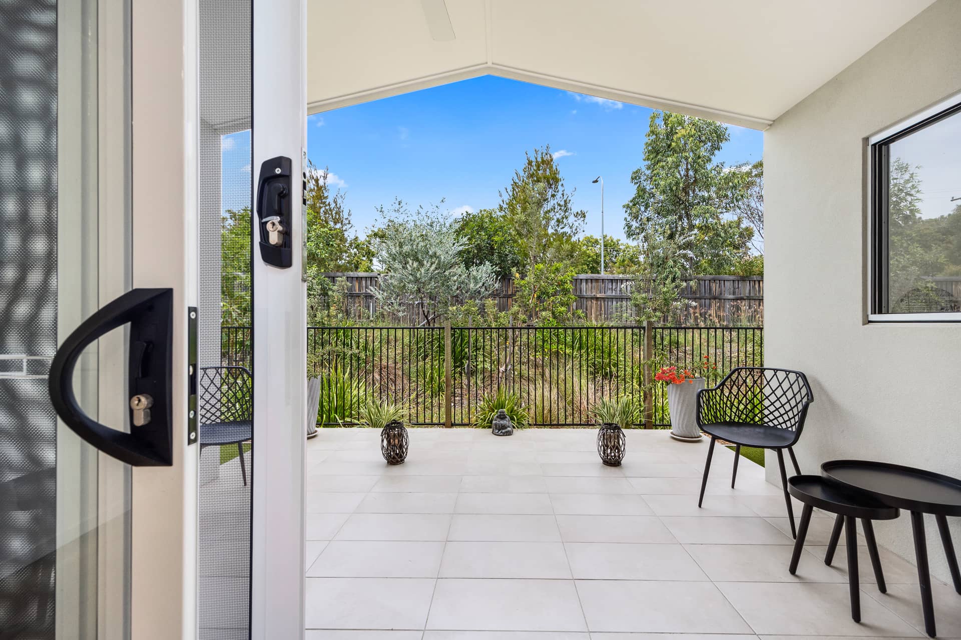 Covered outdoor patio area of an Ingenia Lifestyle home with seating, tiled floor, and garden views.