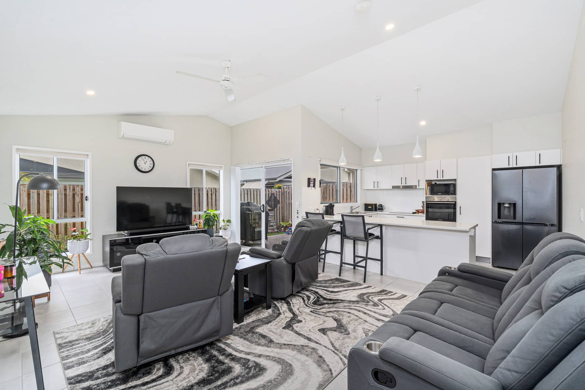 Modern living area and kitchen with lounge seating, a TV, and kitchen island in an Ingenia Lifestyle community.