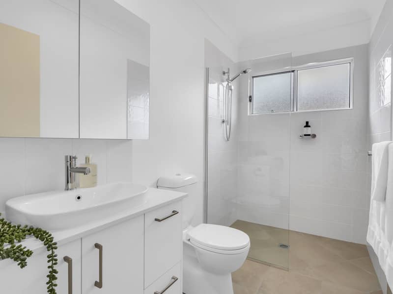 Modern bathroom with a vanity, toilet, and walk-in shower with frosted window.