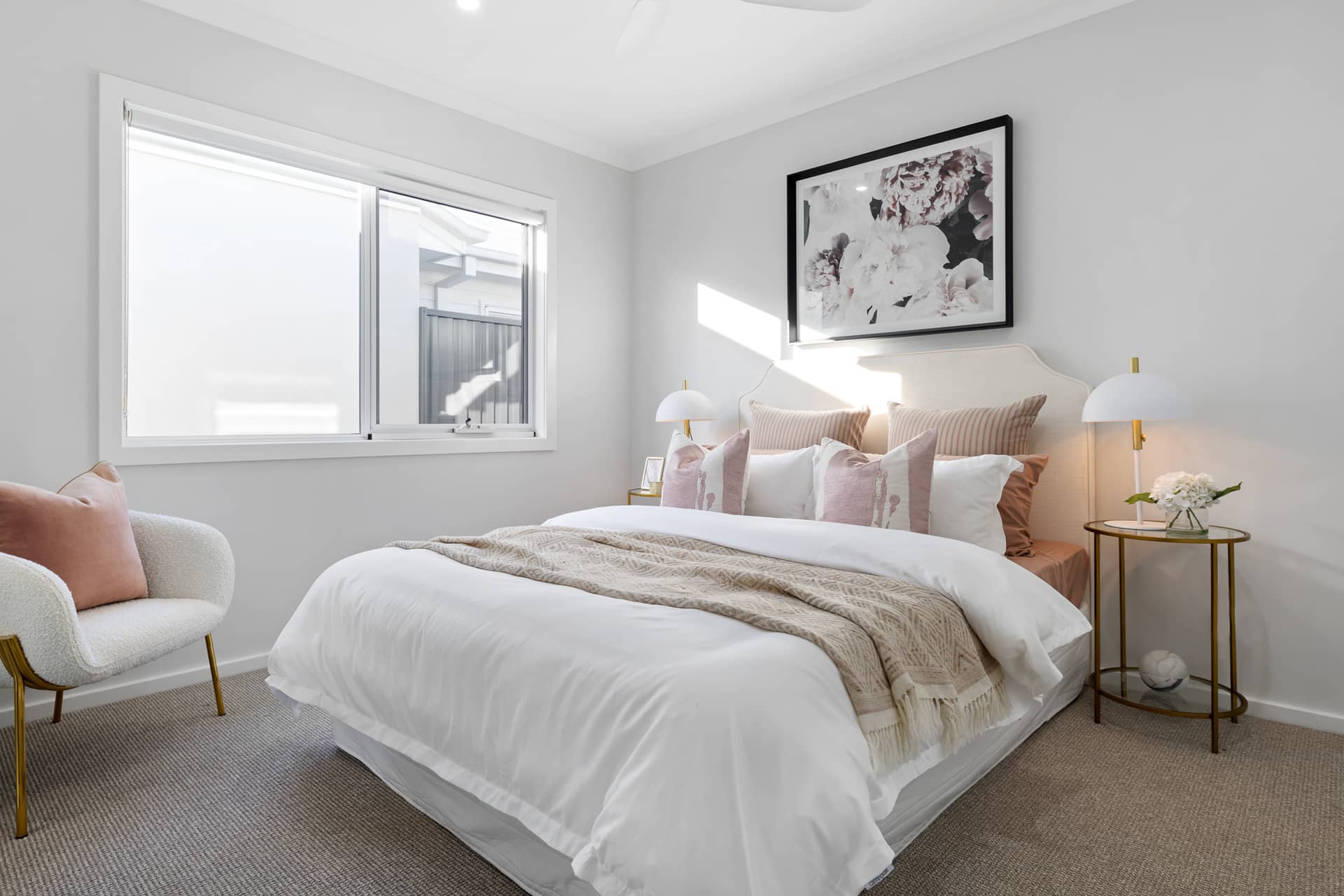 A modern bedroom in an Ingenia Lifestyle community, featuring a white duvet, throw blanket, and plush pillows.