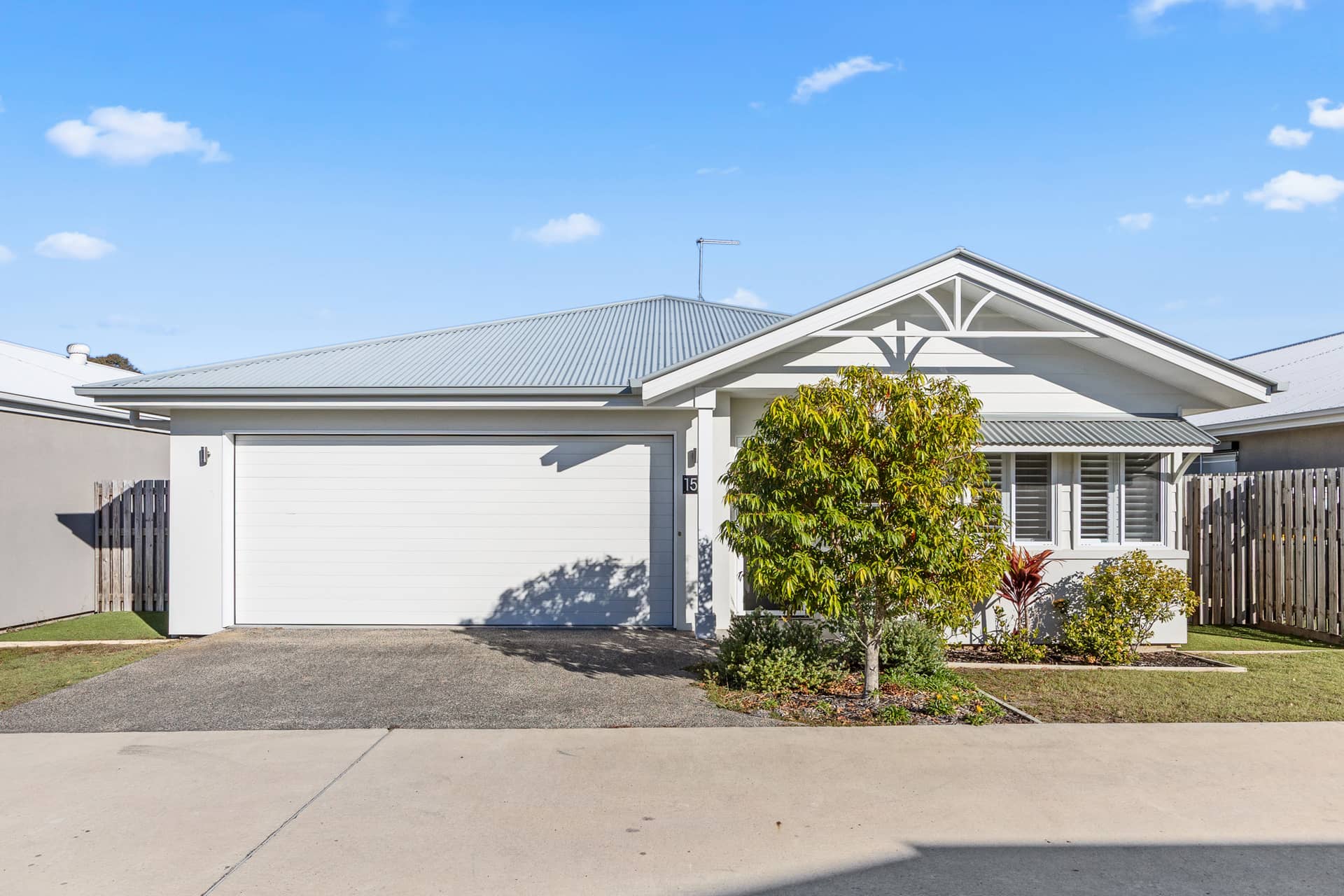 A modern white land lease home in an Ingenia Lifestyle community, featuring a garage, low-maintenance front garden, and grey roof.