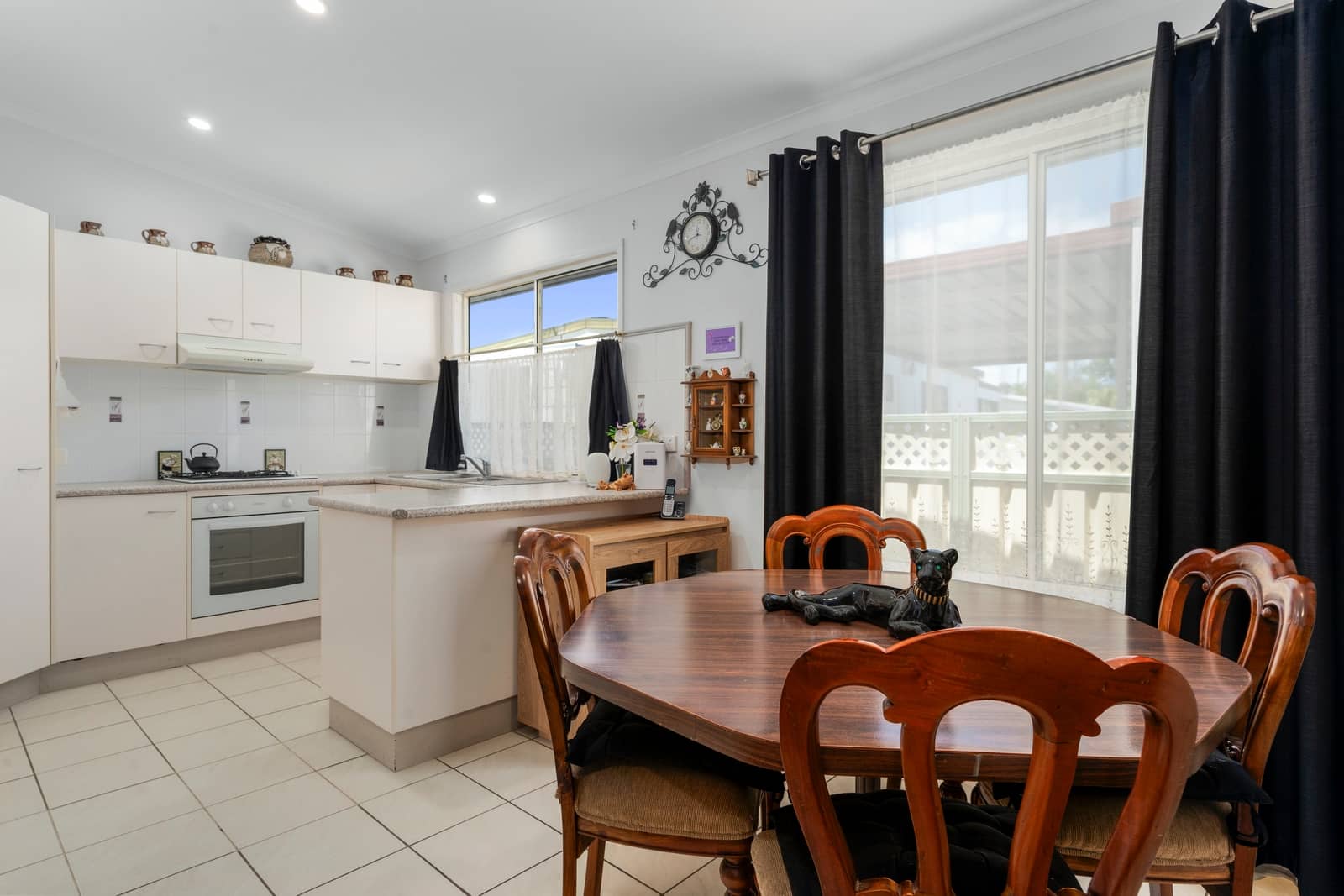 Bright kitchen and dining area in an Ingenia Lifestyle home, with white cabinets, a stove, and a wooden dining table.