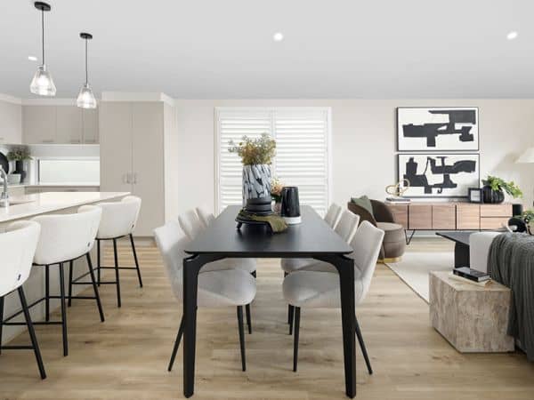 Modern open-plan kitchen and dining area in an Ingenia Lifestyle home, with a black dining table and white bar stools.