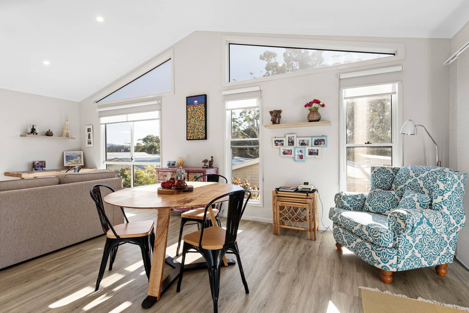 Modern open-plan living and dining space in an Ingenia Lifestyle home, with vaulted ceilings, large windows, and wood-look floors.
