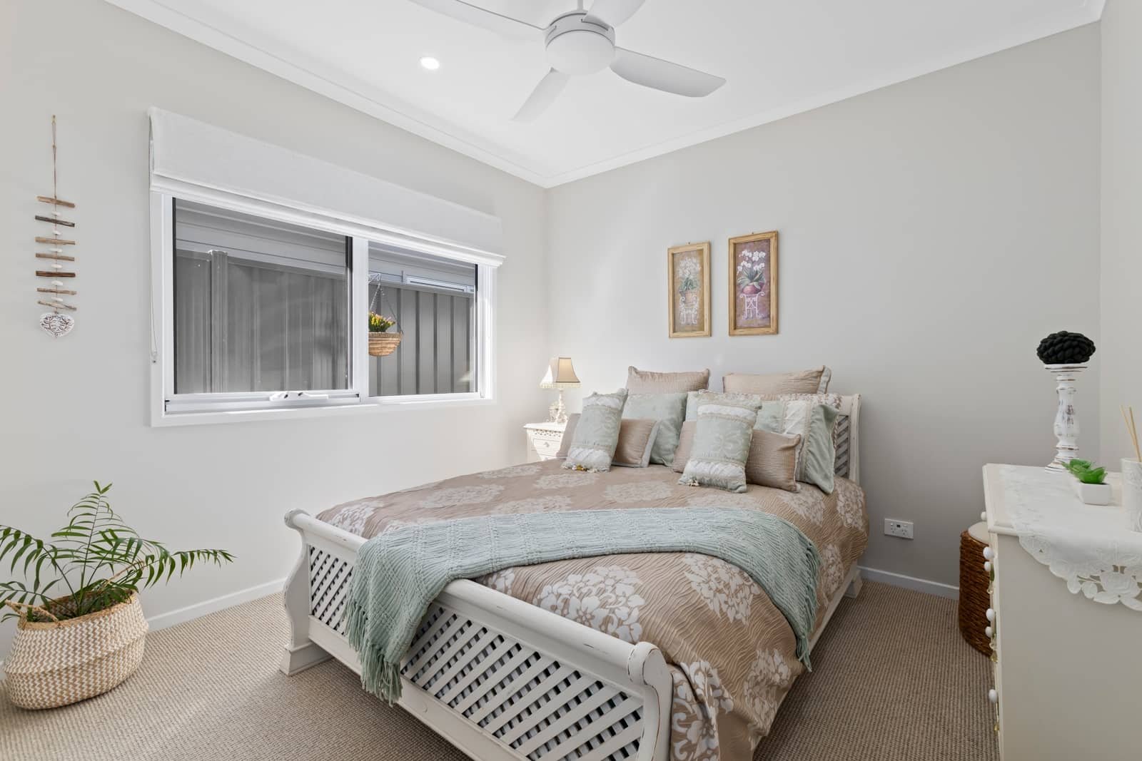 A bright bedroom with a queen bed, decorative pillows, and a mint green throw.