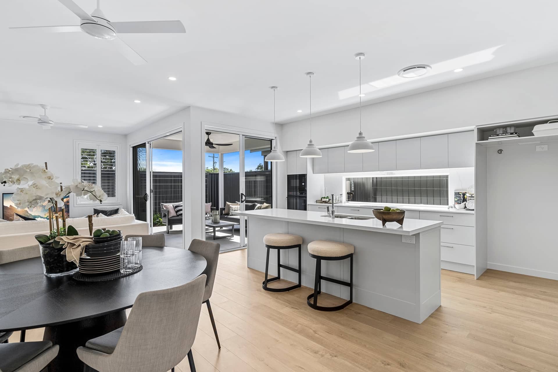 Modern kitchen and dining area with island, stools, and open-plan living space.