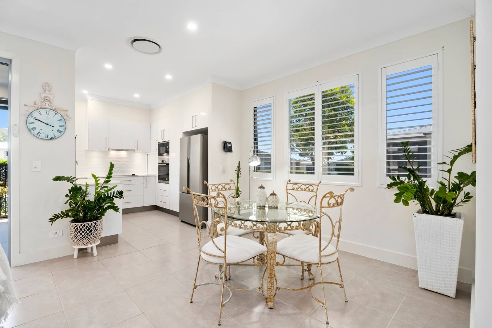 Open-plan kitchen and dining area of an Ingenia Lifestyle home with white cabinets, stainless steel appliances, and a glass table.