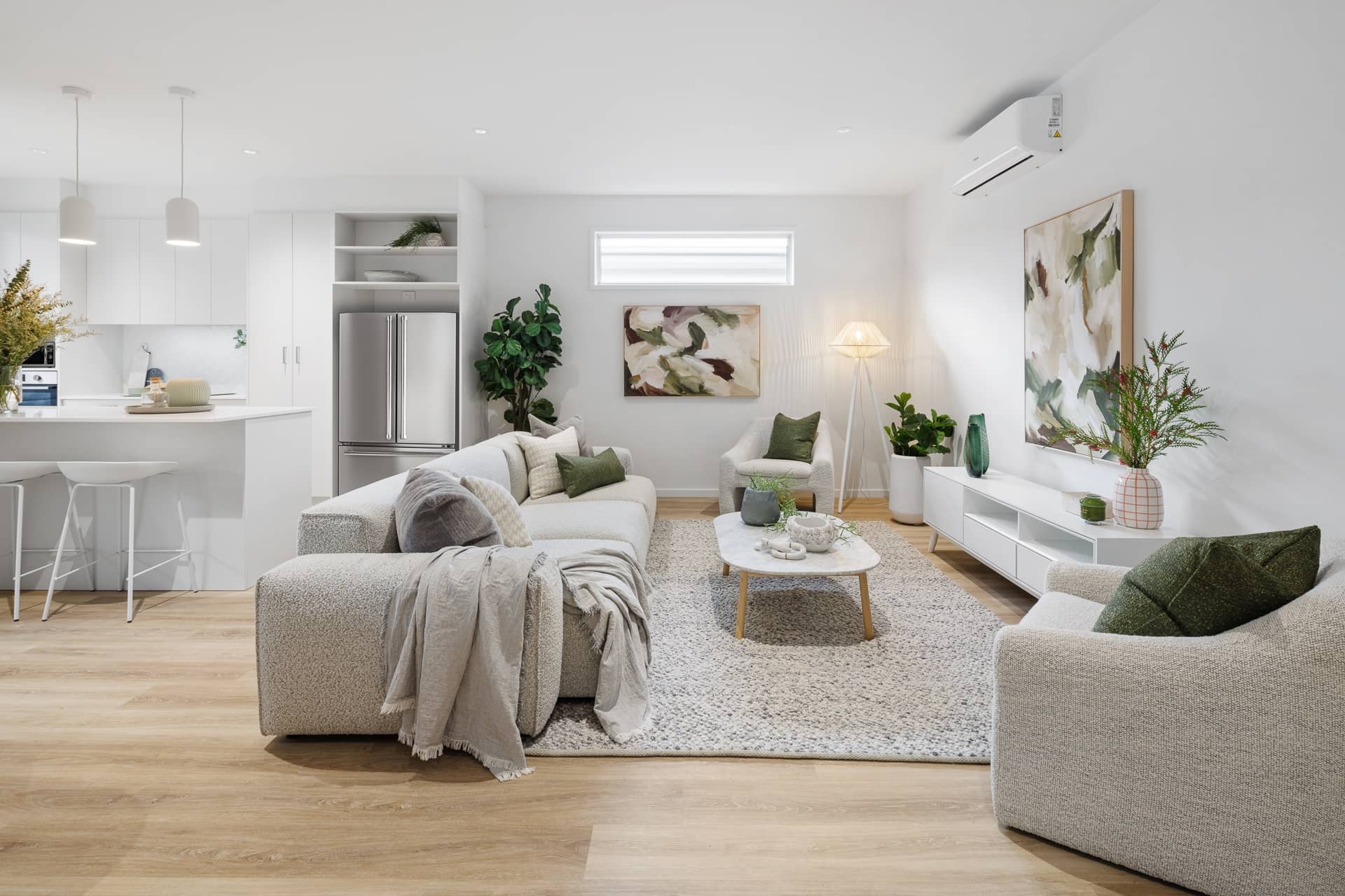 Bright, open-plan living and kitchen space in an Ingenia Lifestyle home, featuring light furniture and wooden floors.
