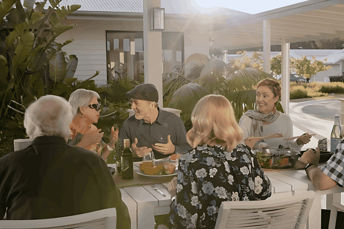 Residents enjoying a social outdoor meal together at a white table in an Ingenia Lifestyle community.