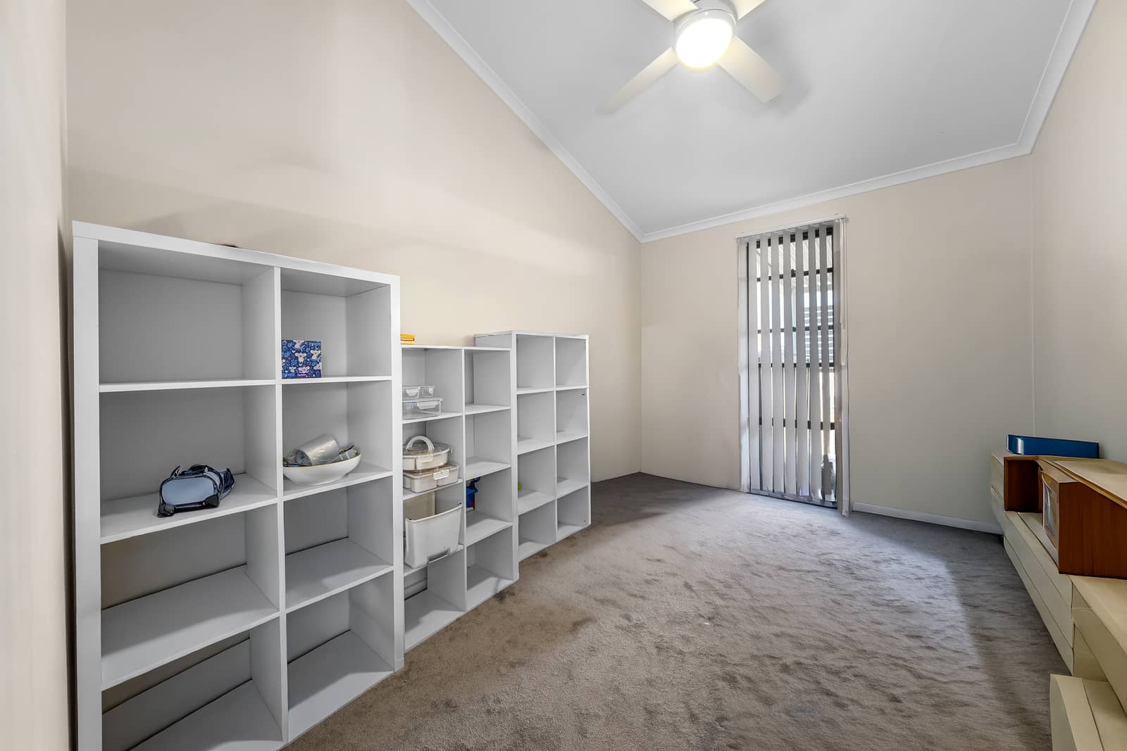 White shelving units are in a room with neutral walls and carpet.