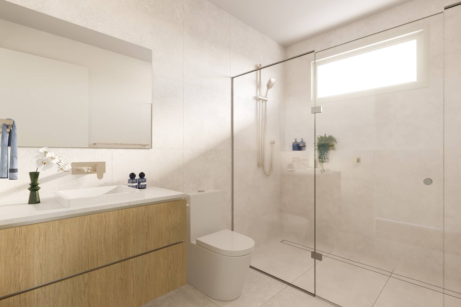 Modern bathroom in an Ingenia Lifestyle home, featuring light tiles, wooden vanity, basin, toilet, and a glass shower.