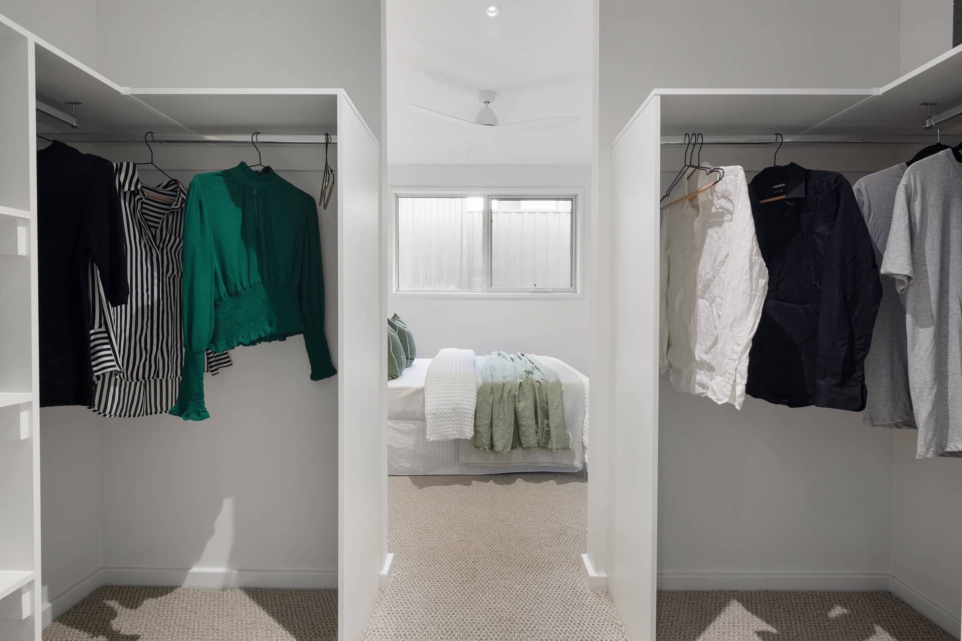 A walk-through wardrobe with built-in storage for clothes, leading to a bright bedroom in an Ingenia Lifestyle home.