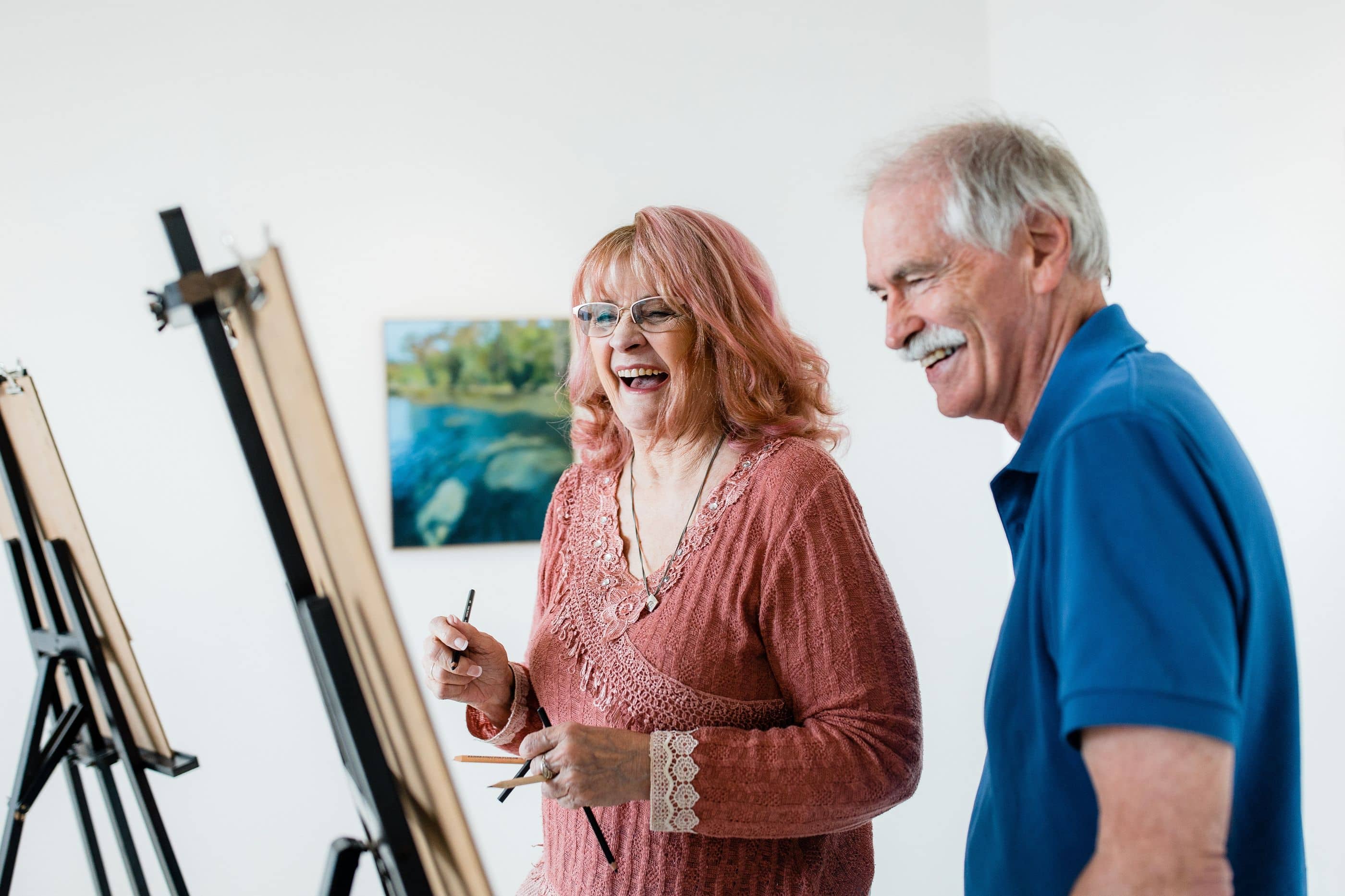 Two people smiling whilst doing an art class.
