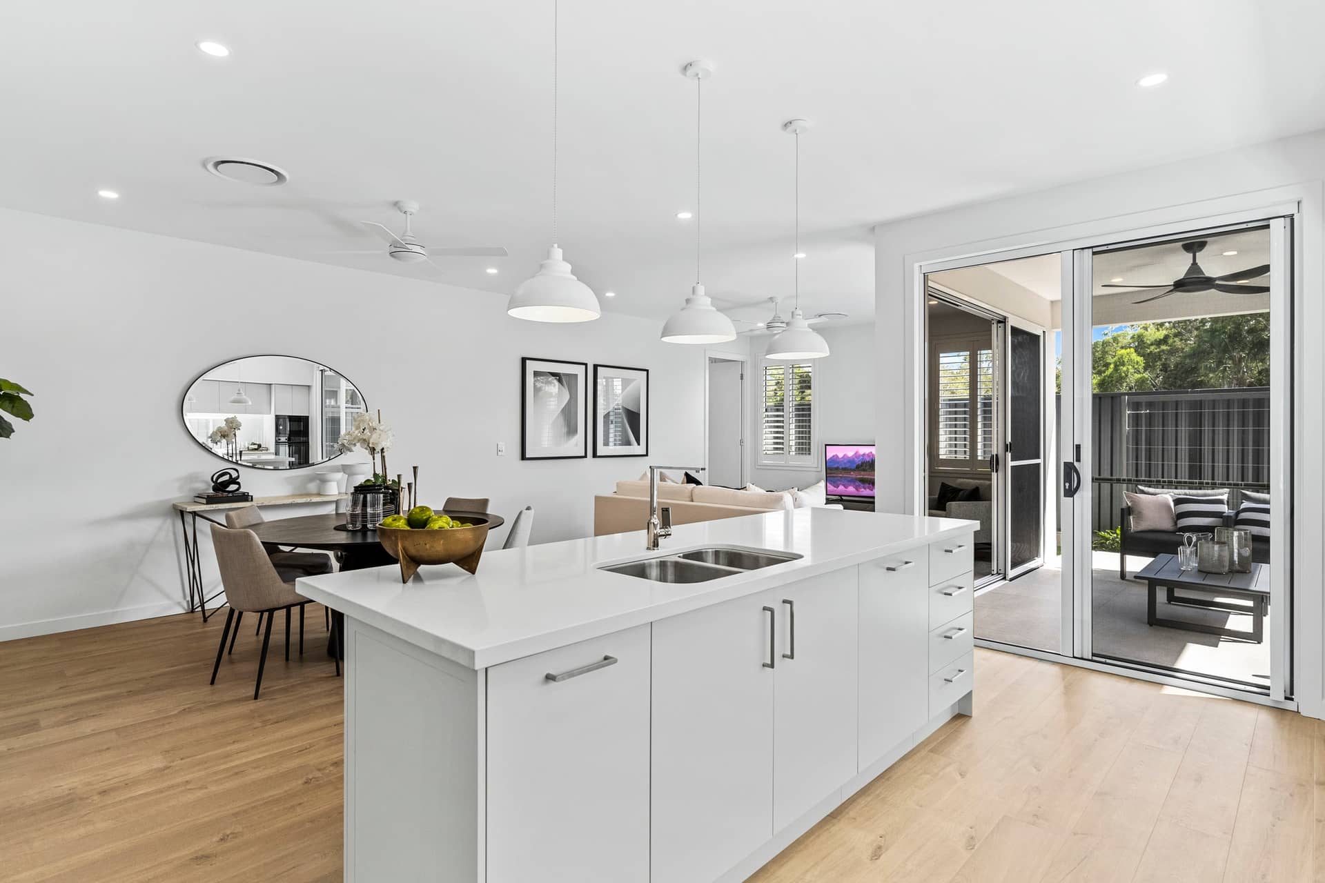 Modern kitchen island with sink, overlooking dining and living areas, and outdoor patio.