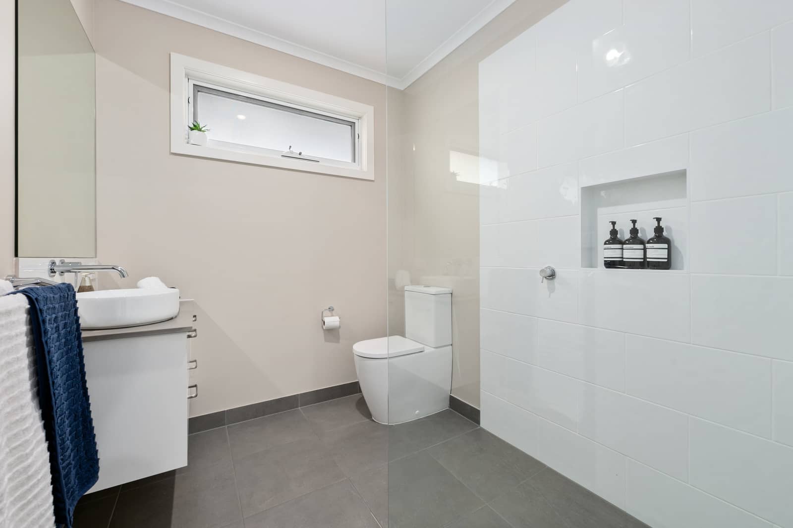 Modern bathroom in an Ingenia Lifestyle home with a vanity, white toilet, and walk-in shower with subway tiles.