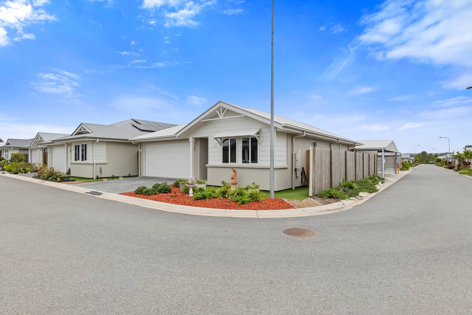 Residential street view of modern Ingenia Lifestyle homes, featuring garages and neat, low-maintenance front gardens.