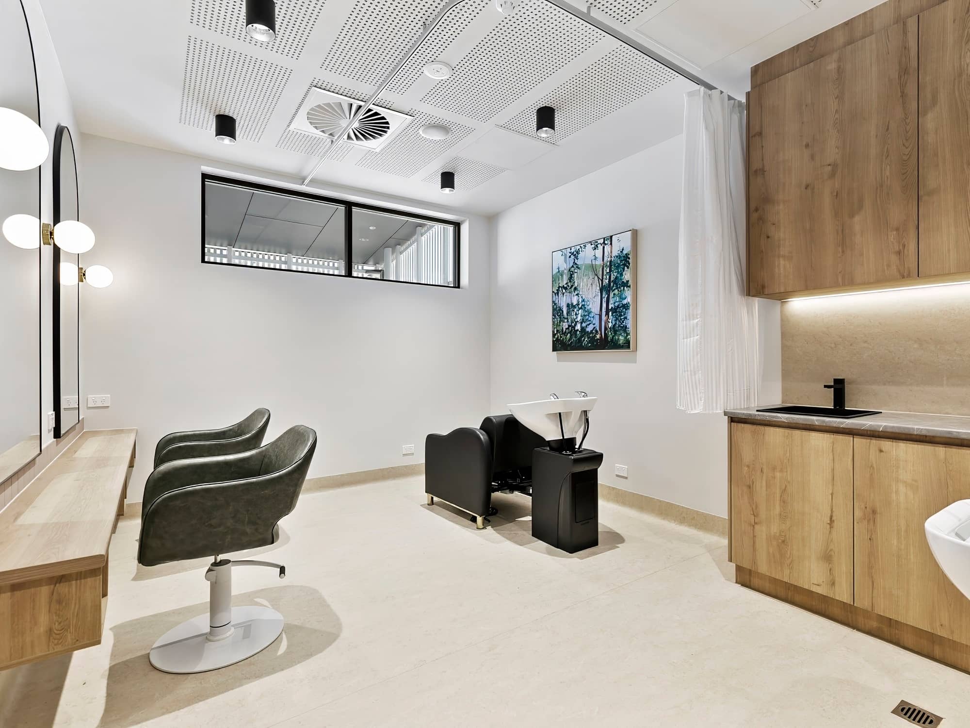 A modern hair salon space within an Ingenia Lifestyle community, featuring styling chairs, a hair washing station, and wooden cabinetry.